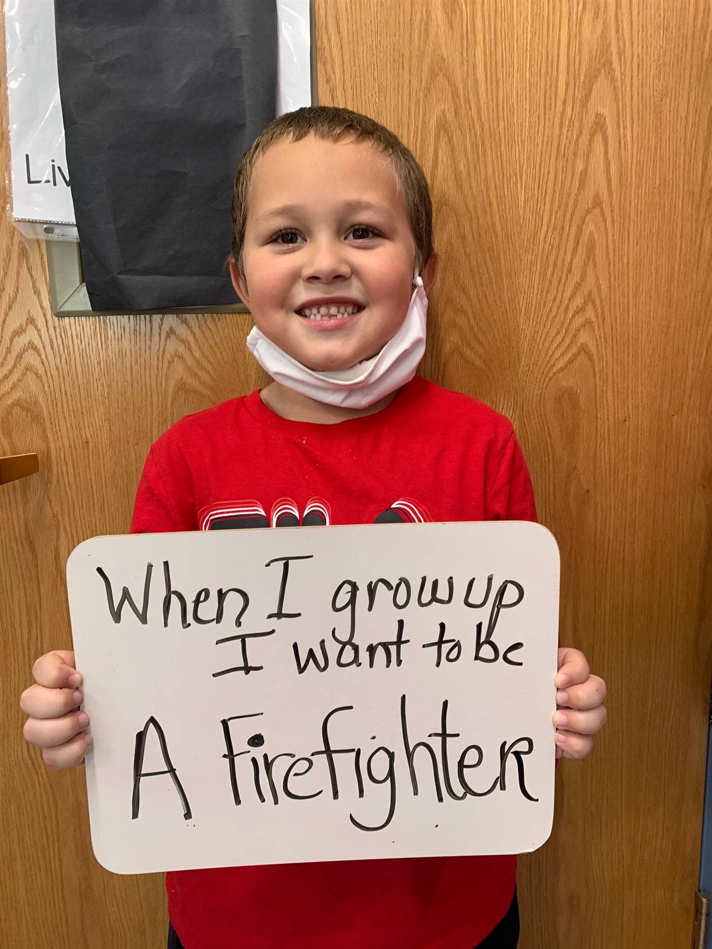 child holding sign "when i grow up I want to be a firefighter"
