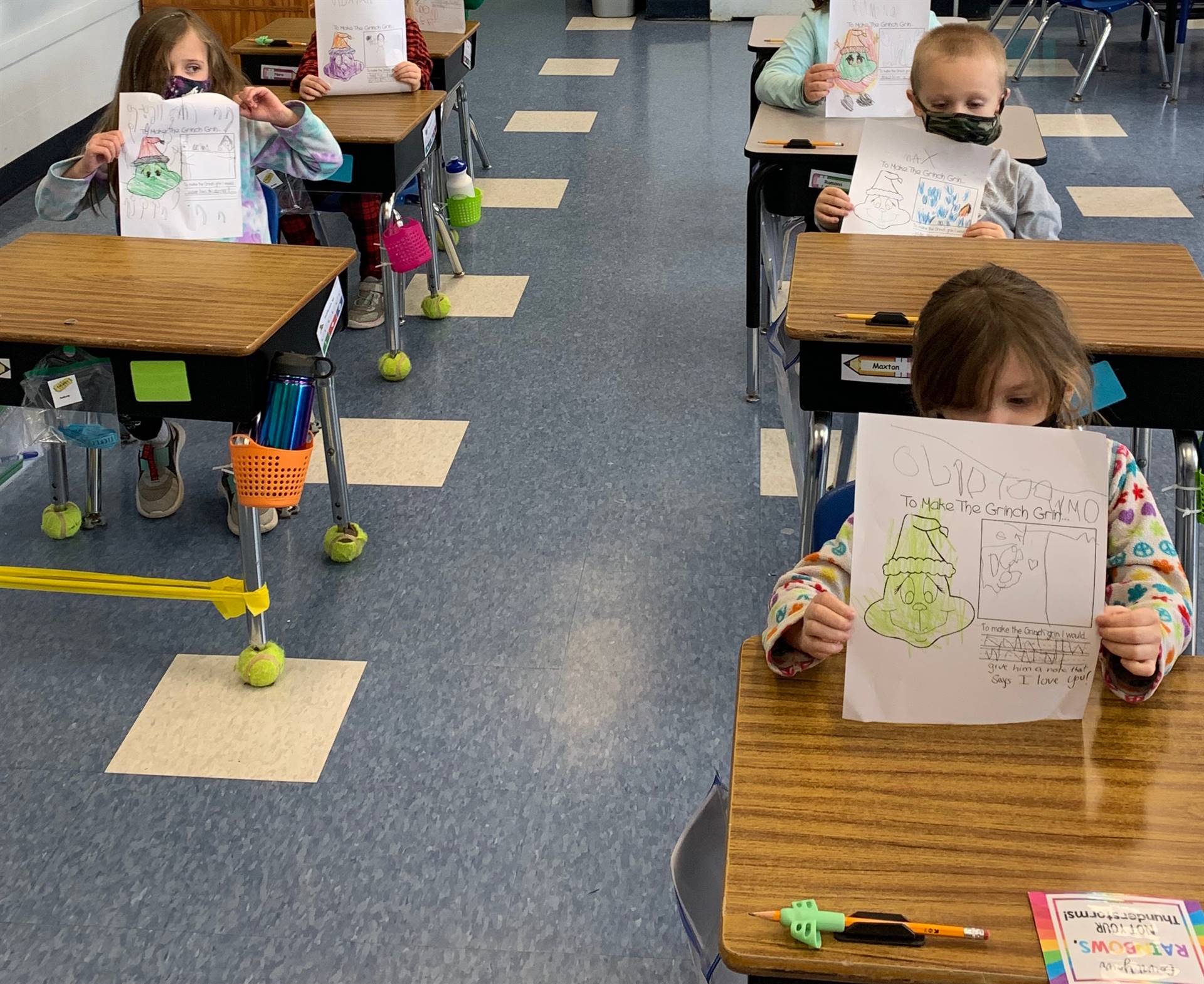 Students hold up pictures of grinch with words "I can make the grinch grin by"