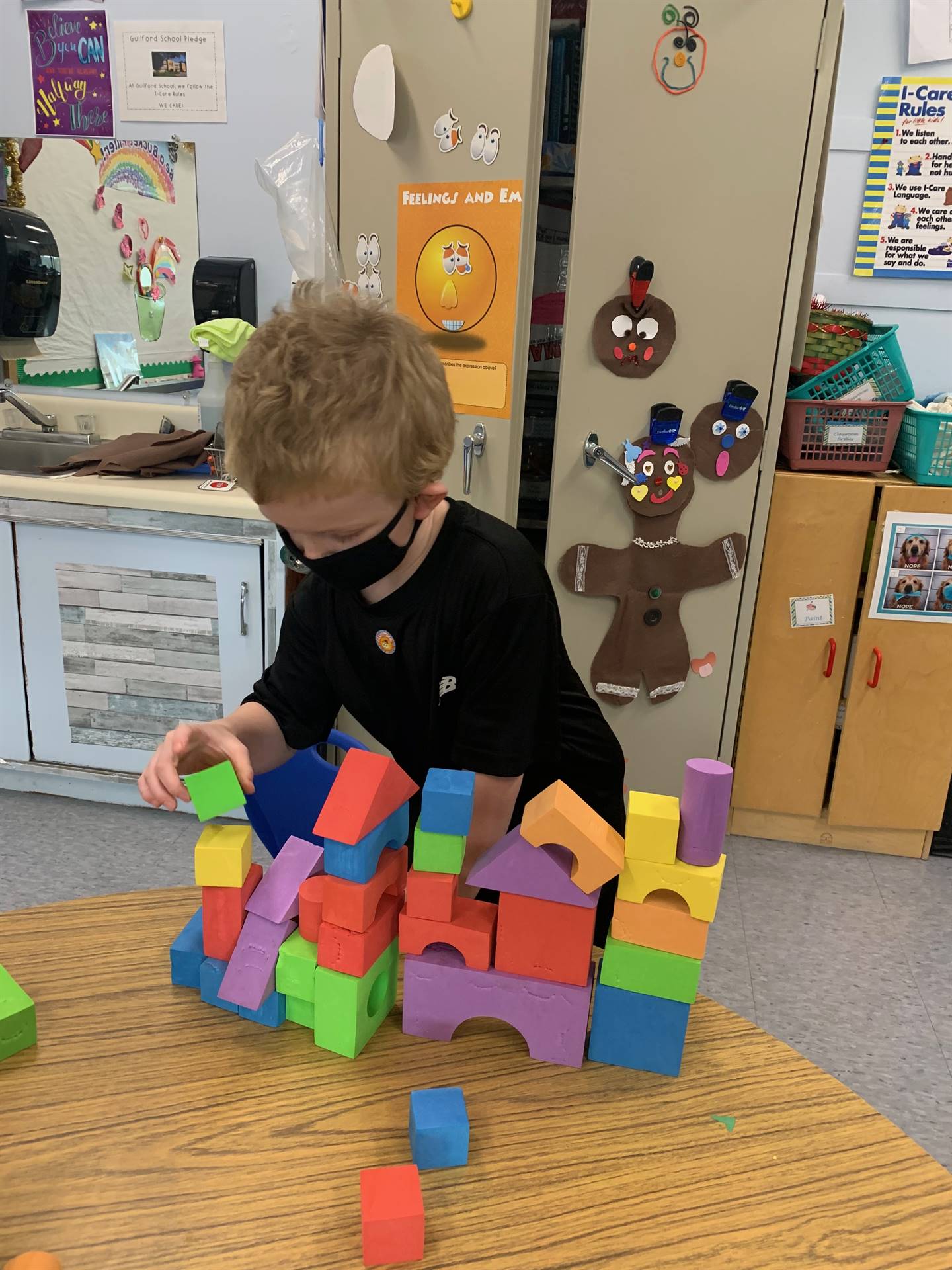 A student places a block on a structure he is building.