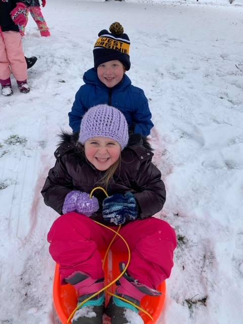 2 students on a sled outside.