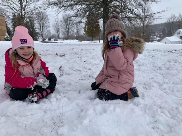 2 students sitting in snow.