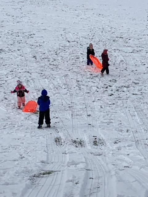 4 students carrying a sled outside in snow.