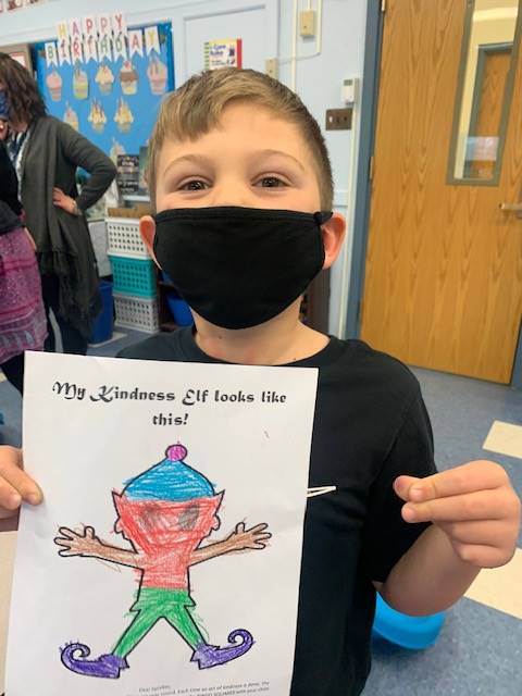 student holding up a picture of colored elf on paper