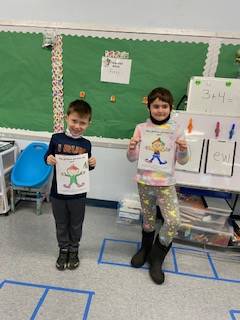 2 students holding up a colored picture of an elf.