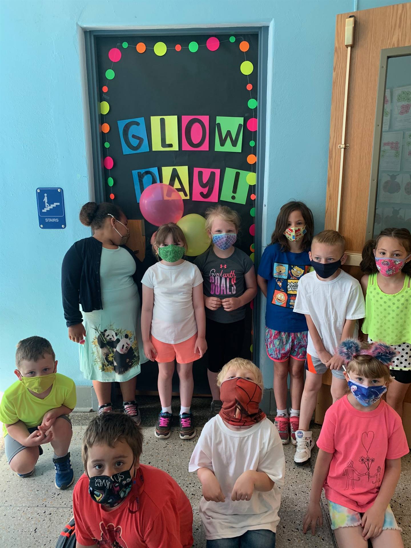 Students in front of door with "Glow day" sign in bright neon letters