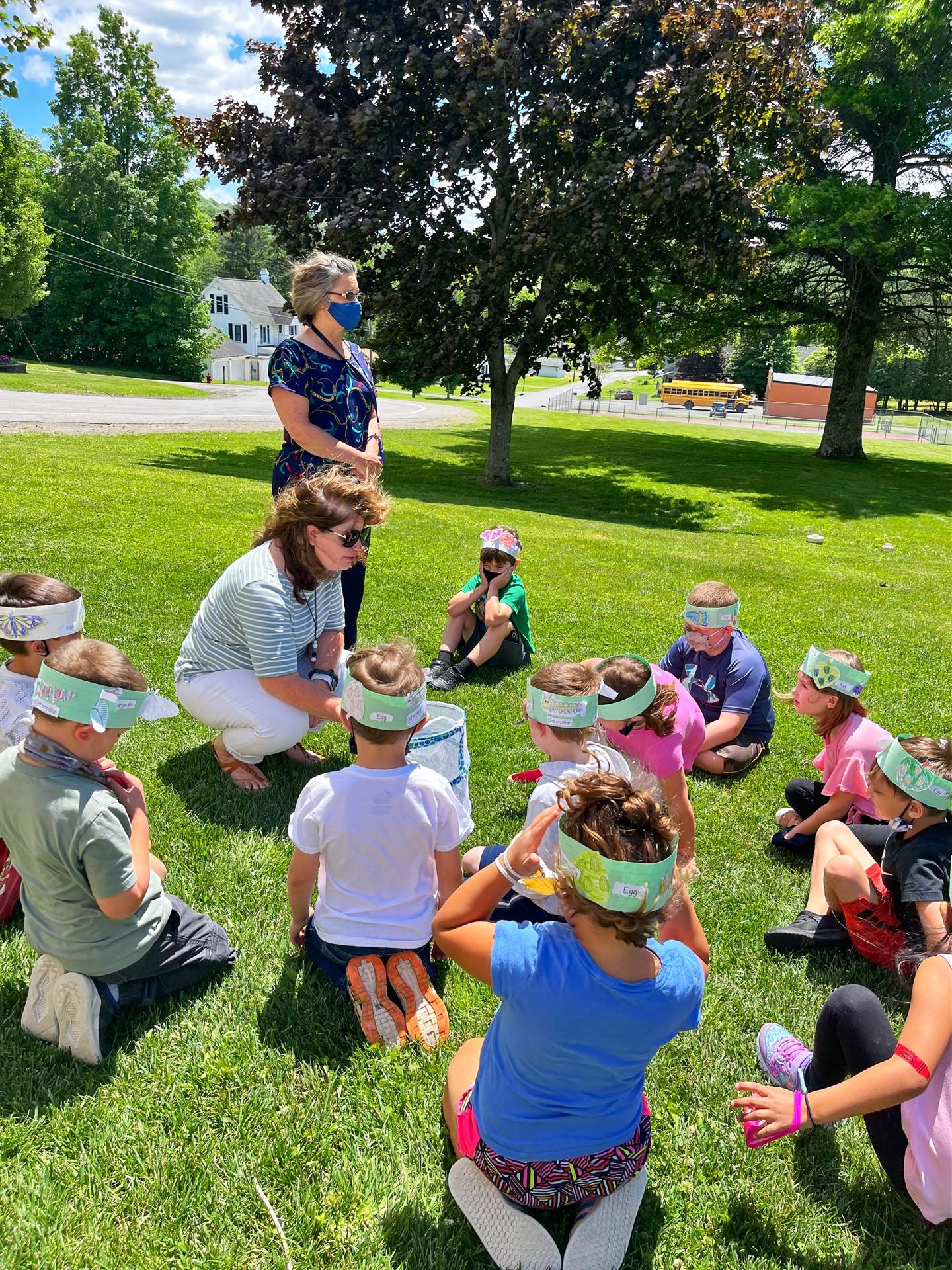 teacher and students letting butterflies out of cage.