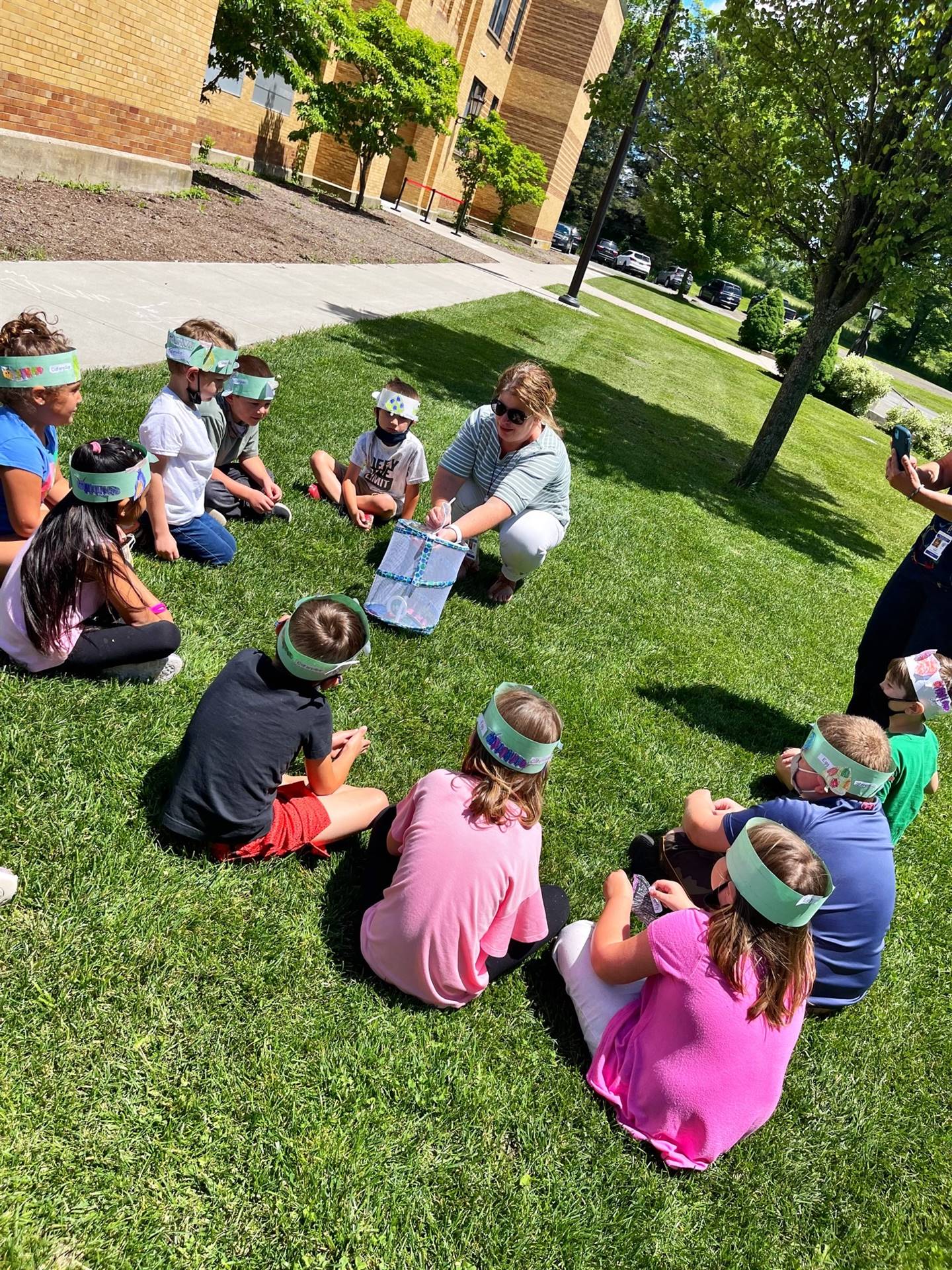 teacher and students letting butterflies out of cage.