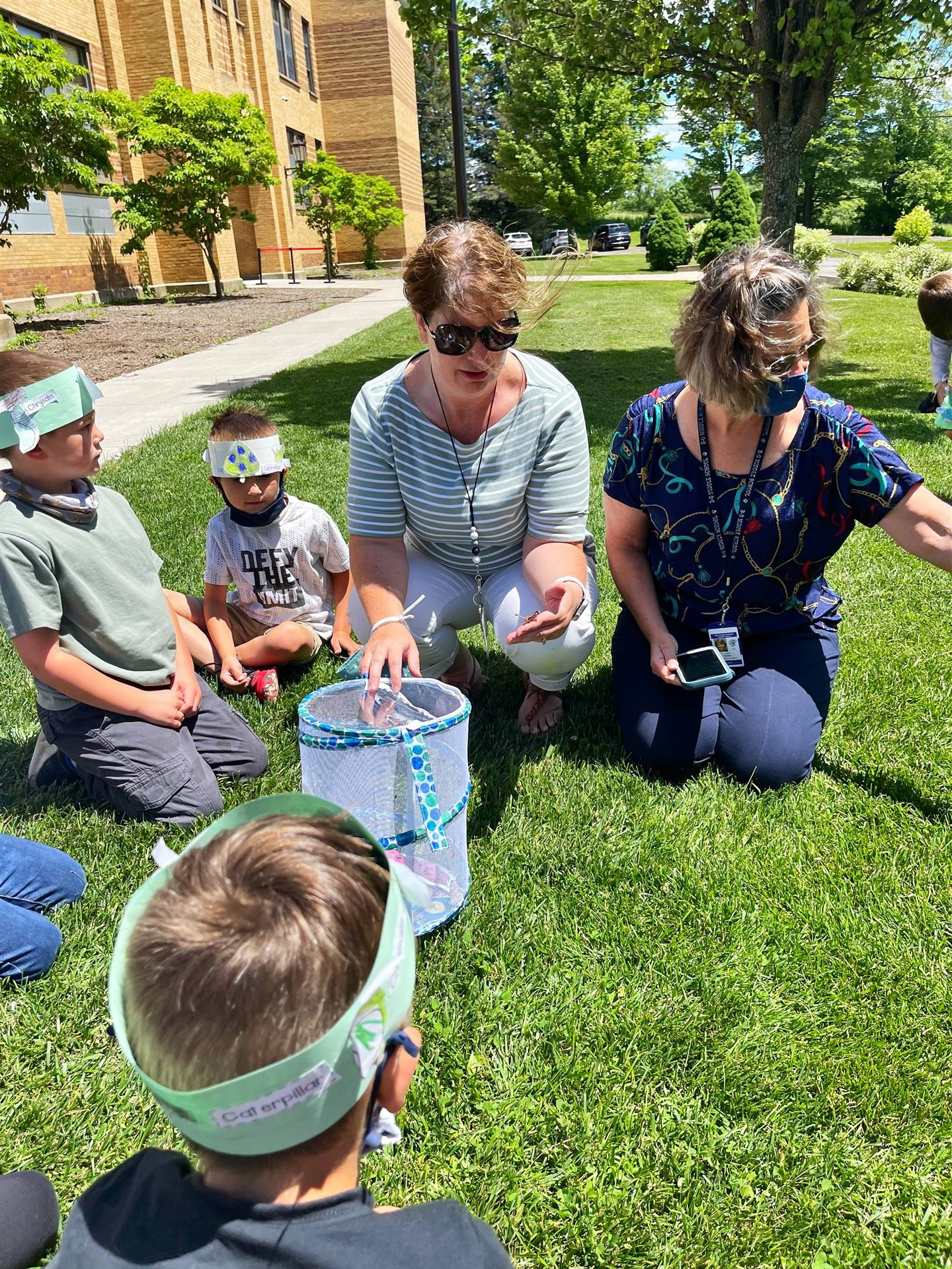 2 adults and staff with butterflies and students.