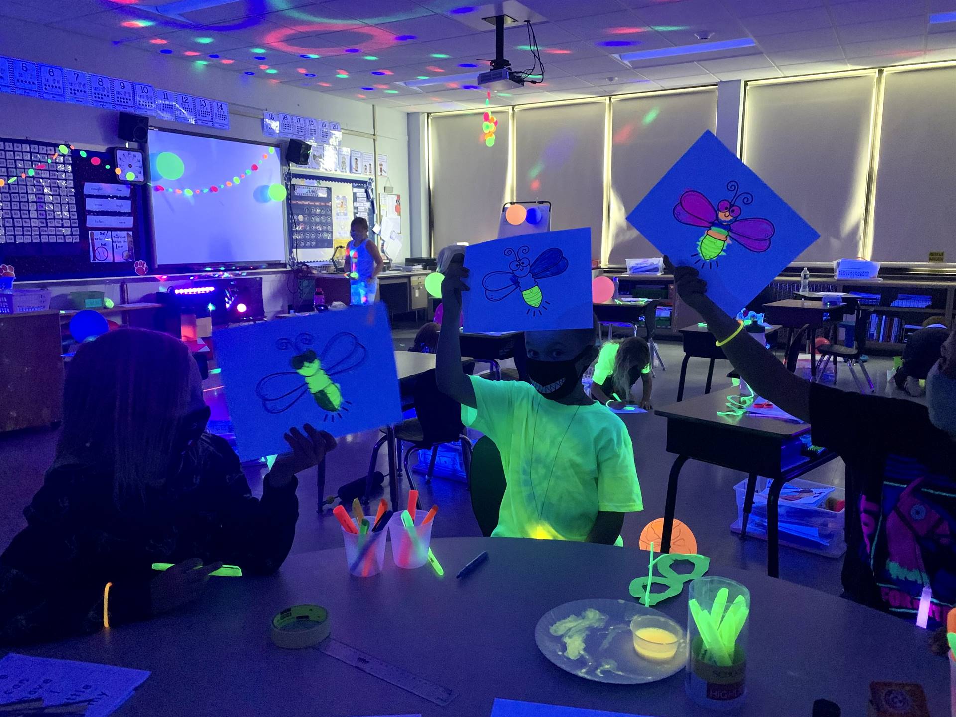 3 students hold up glow up butterflies