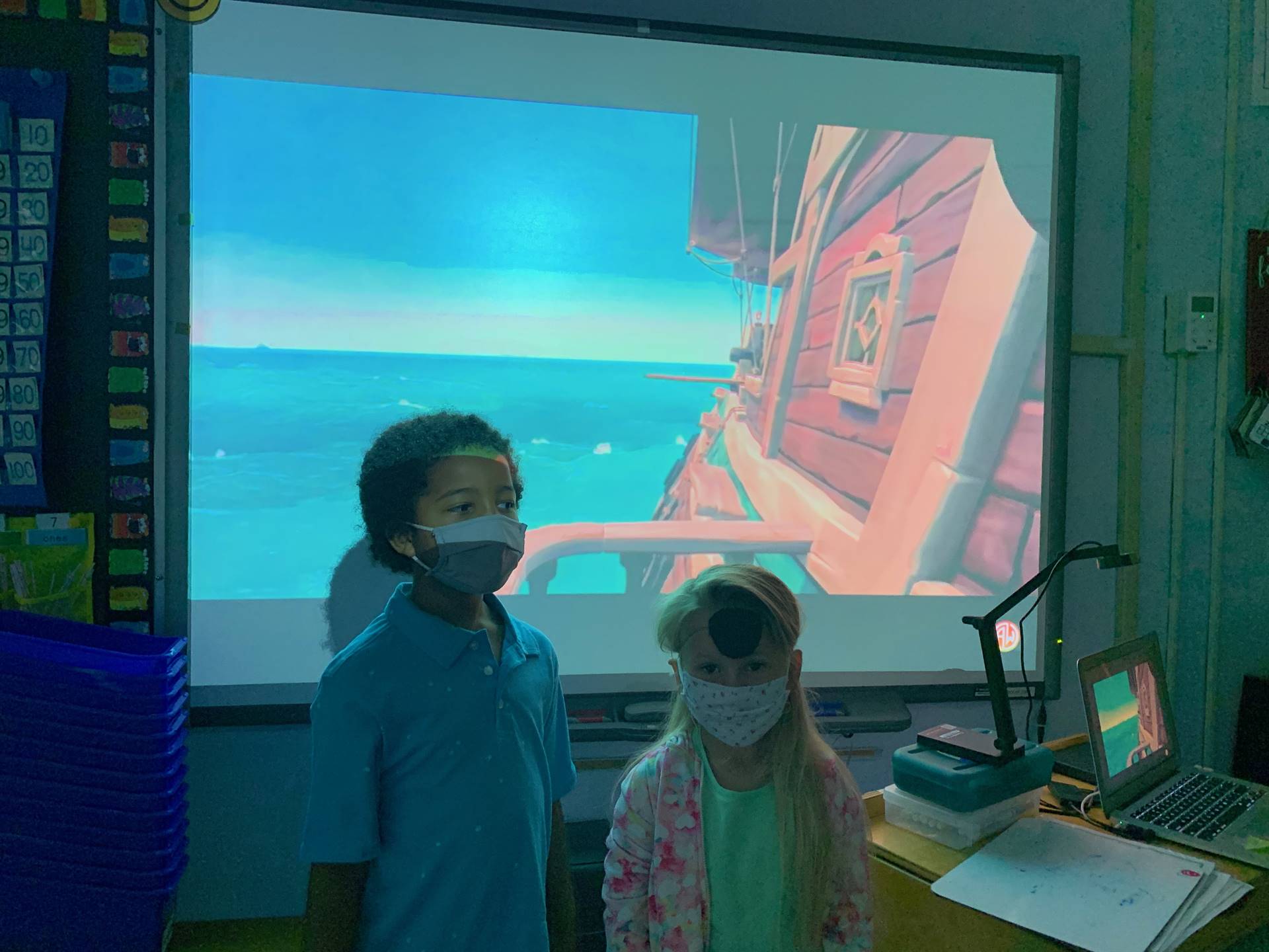 2 students in front of a ship backdrop.