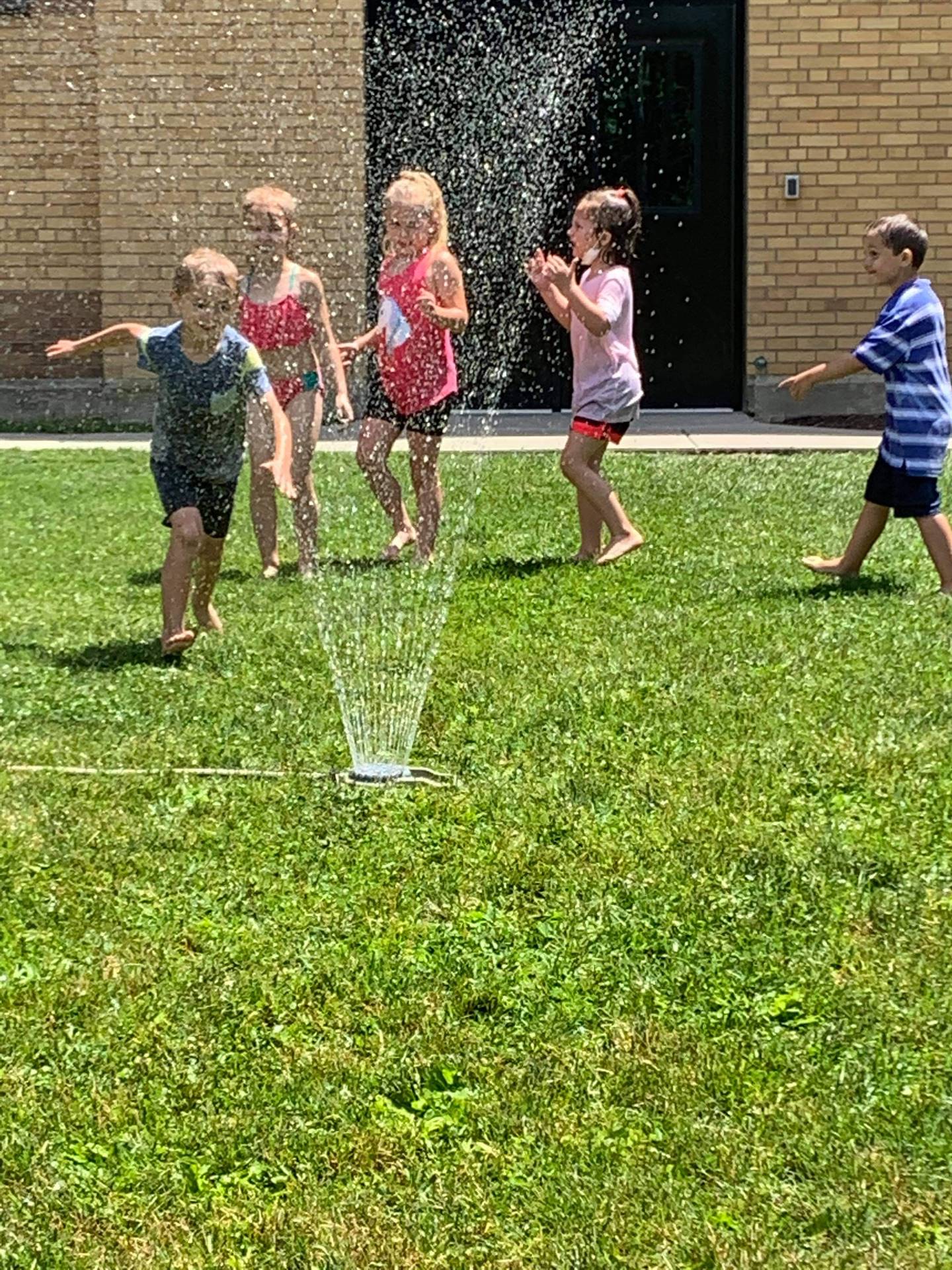 students running under sprinkler