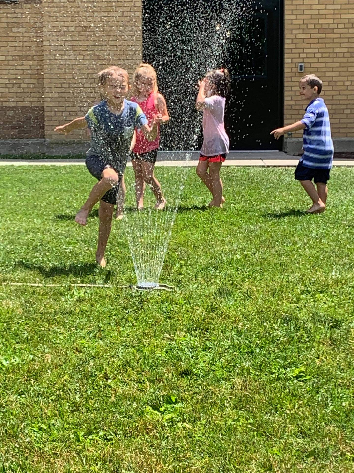 students running under sprinkler