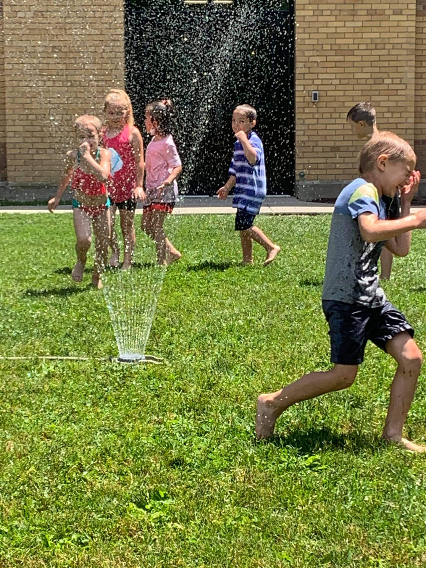 students running under sprinkler