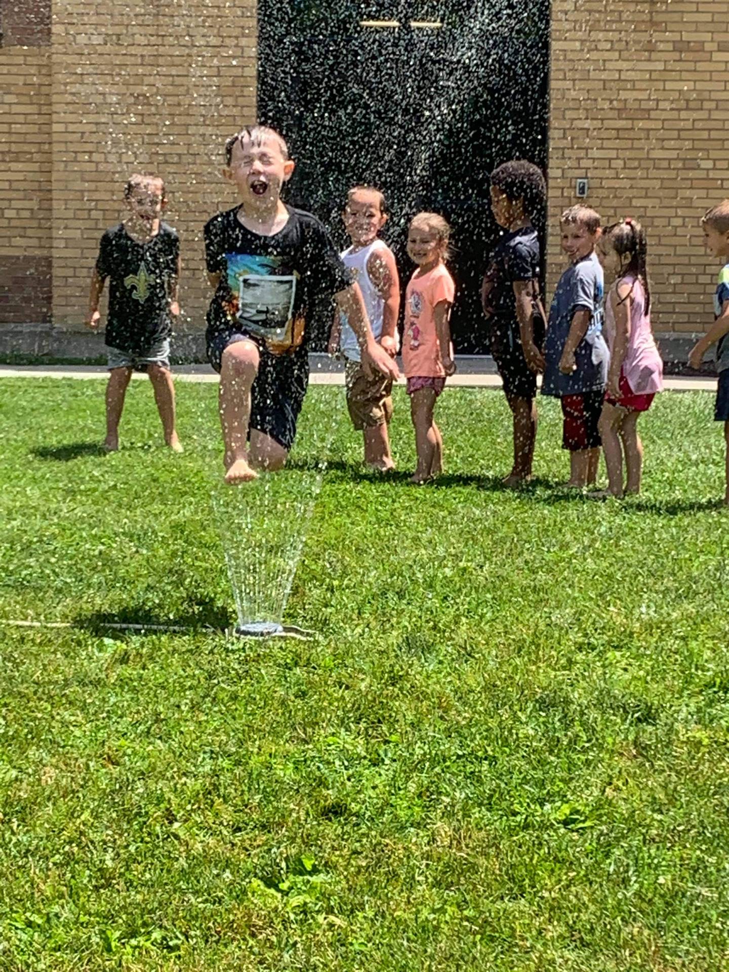 students running under sprinkler