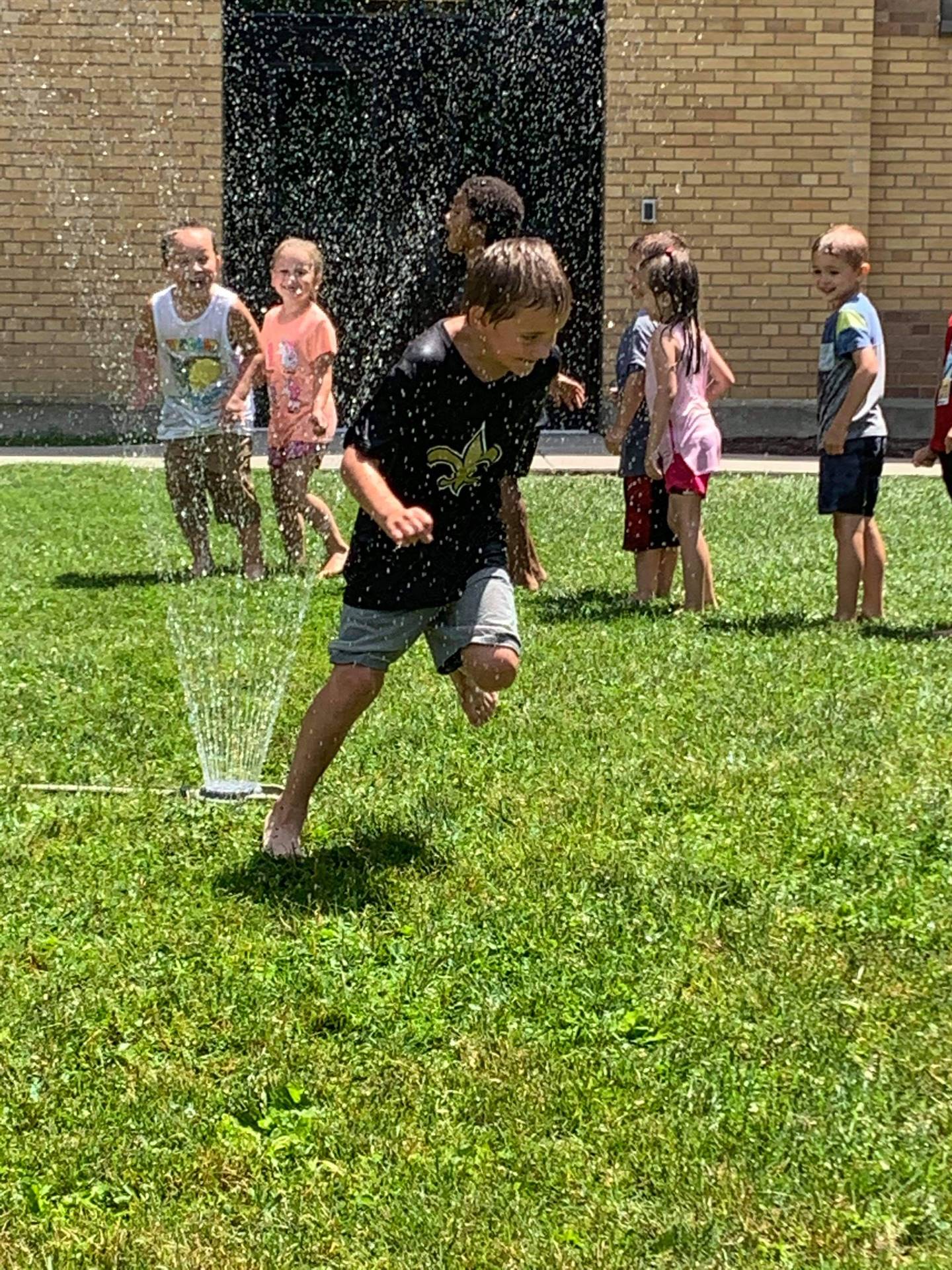 students running under sprinkler