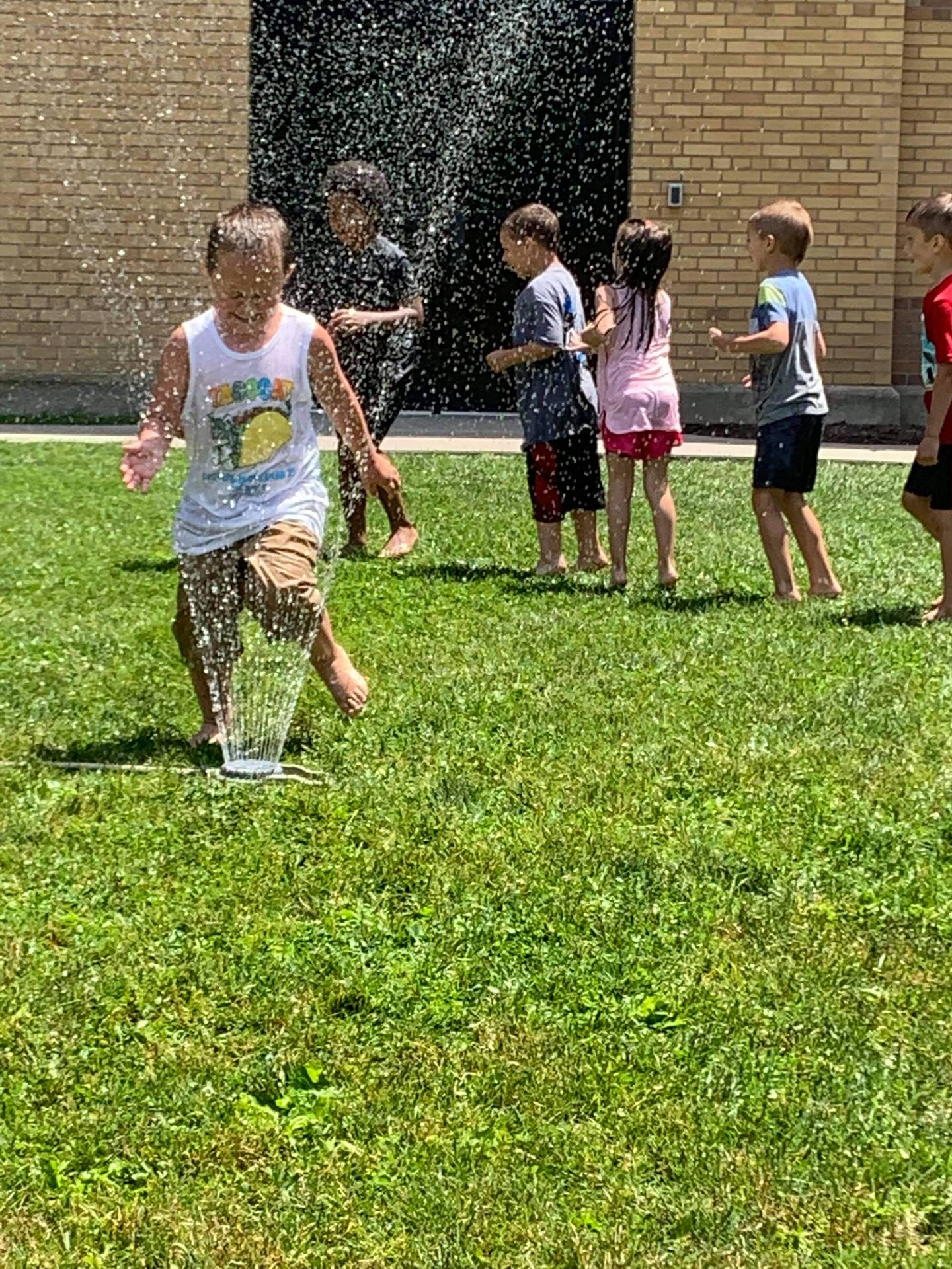 students running under sprinkler