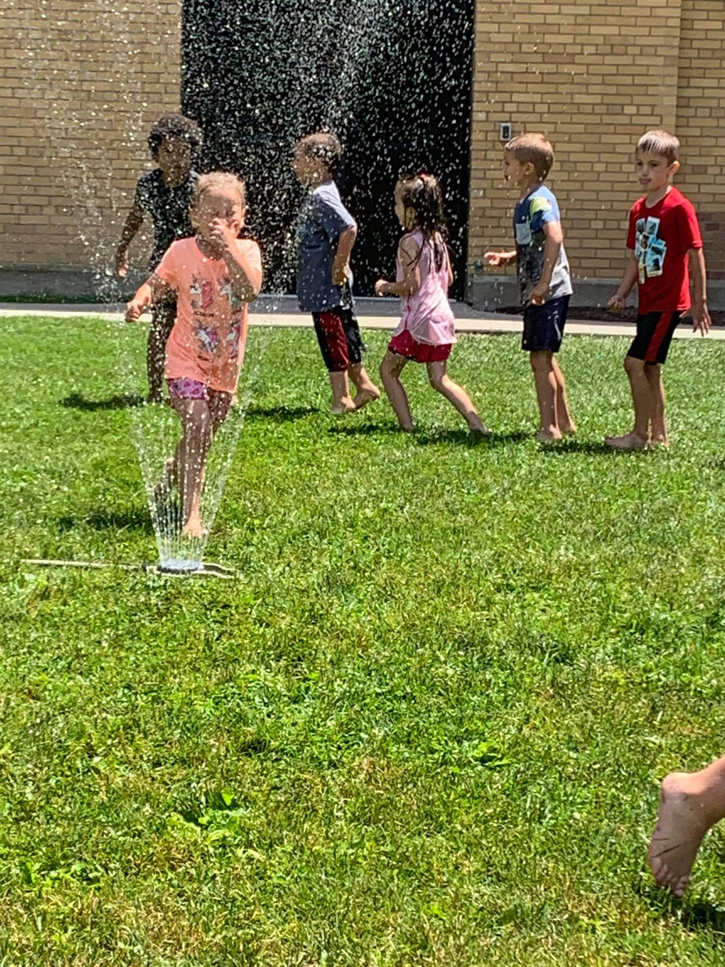 students running under sprinkler