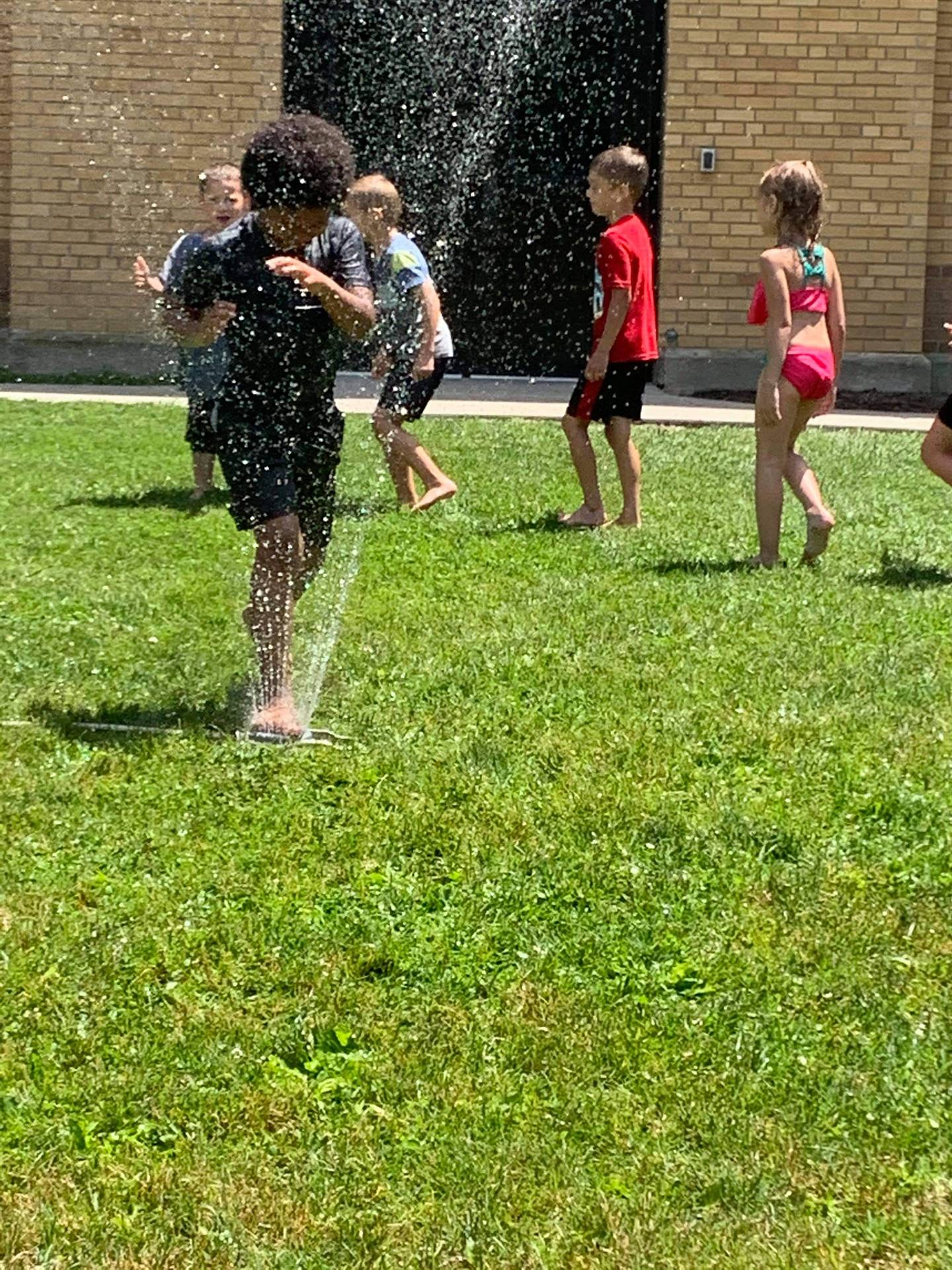 students running under sprinkler