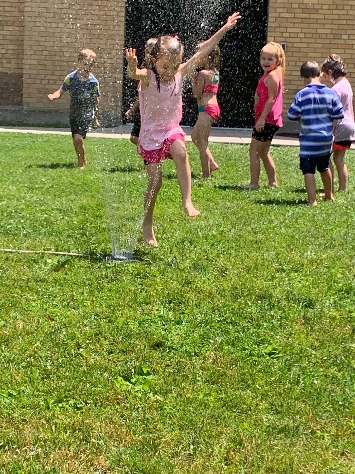 students running under sprinkler