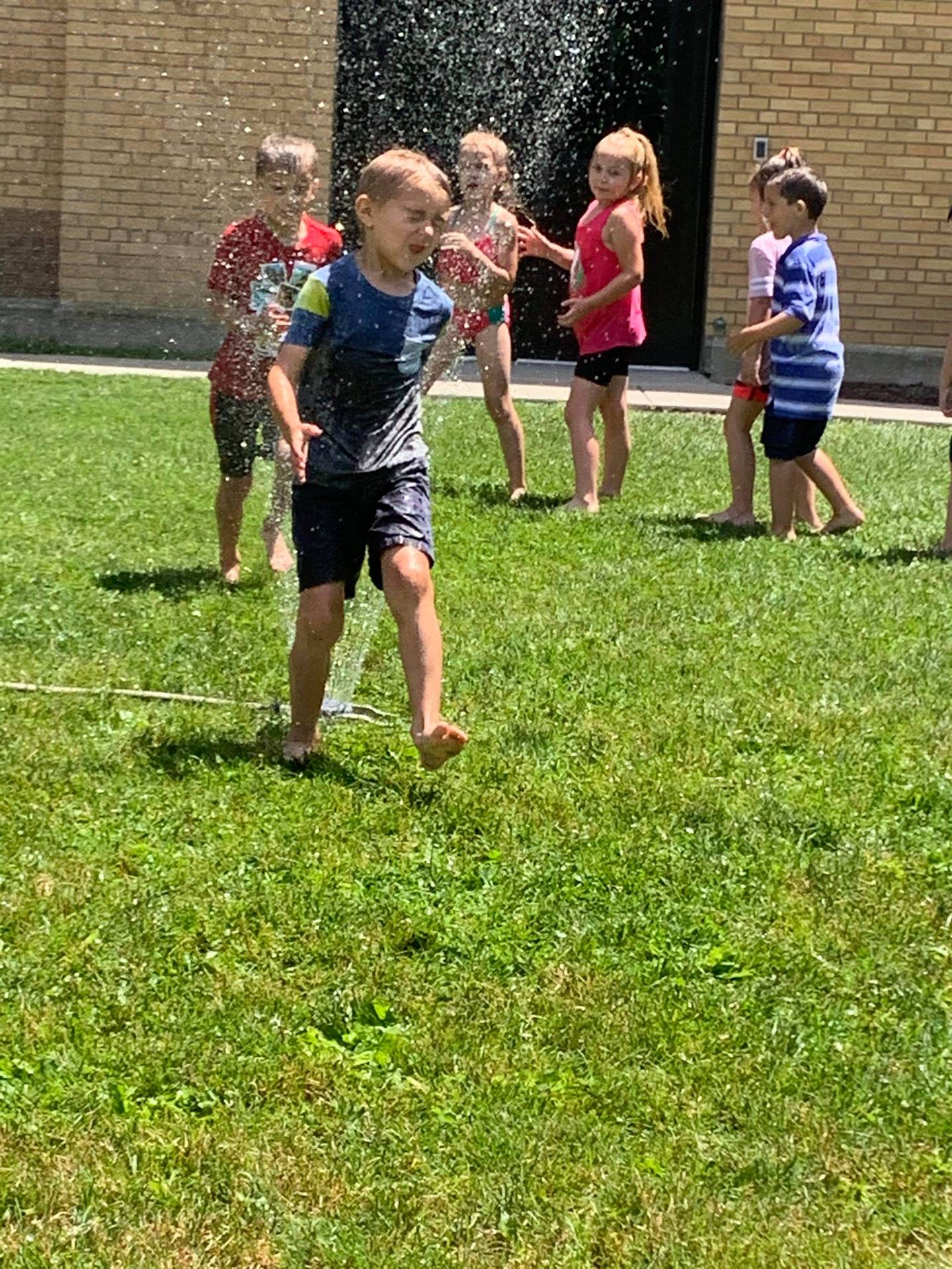 students running under sprinkler