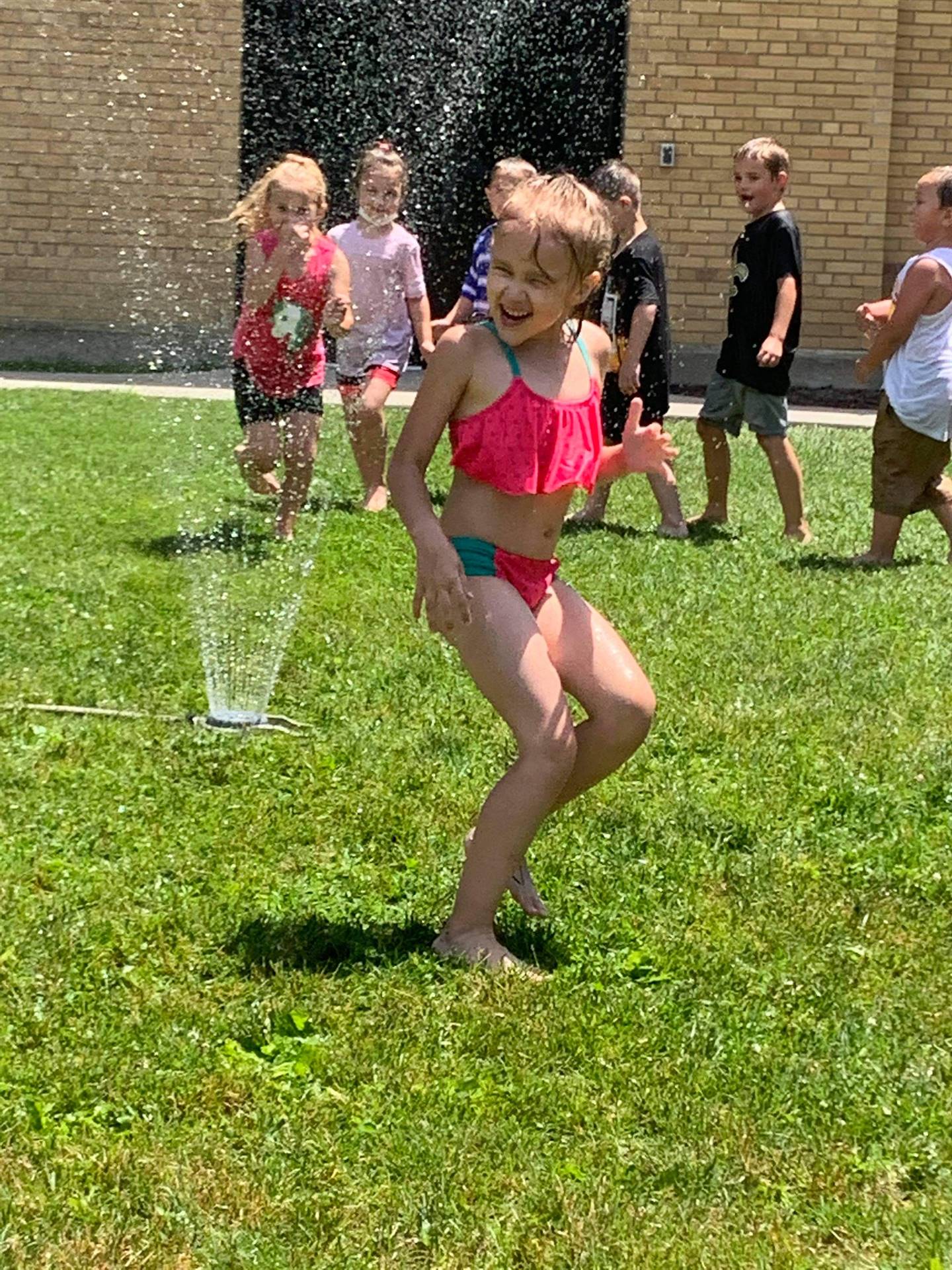 students running under sprinkler