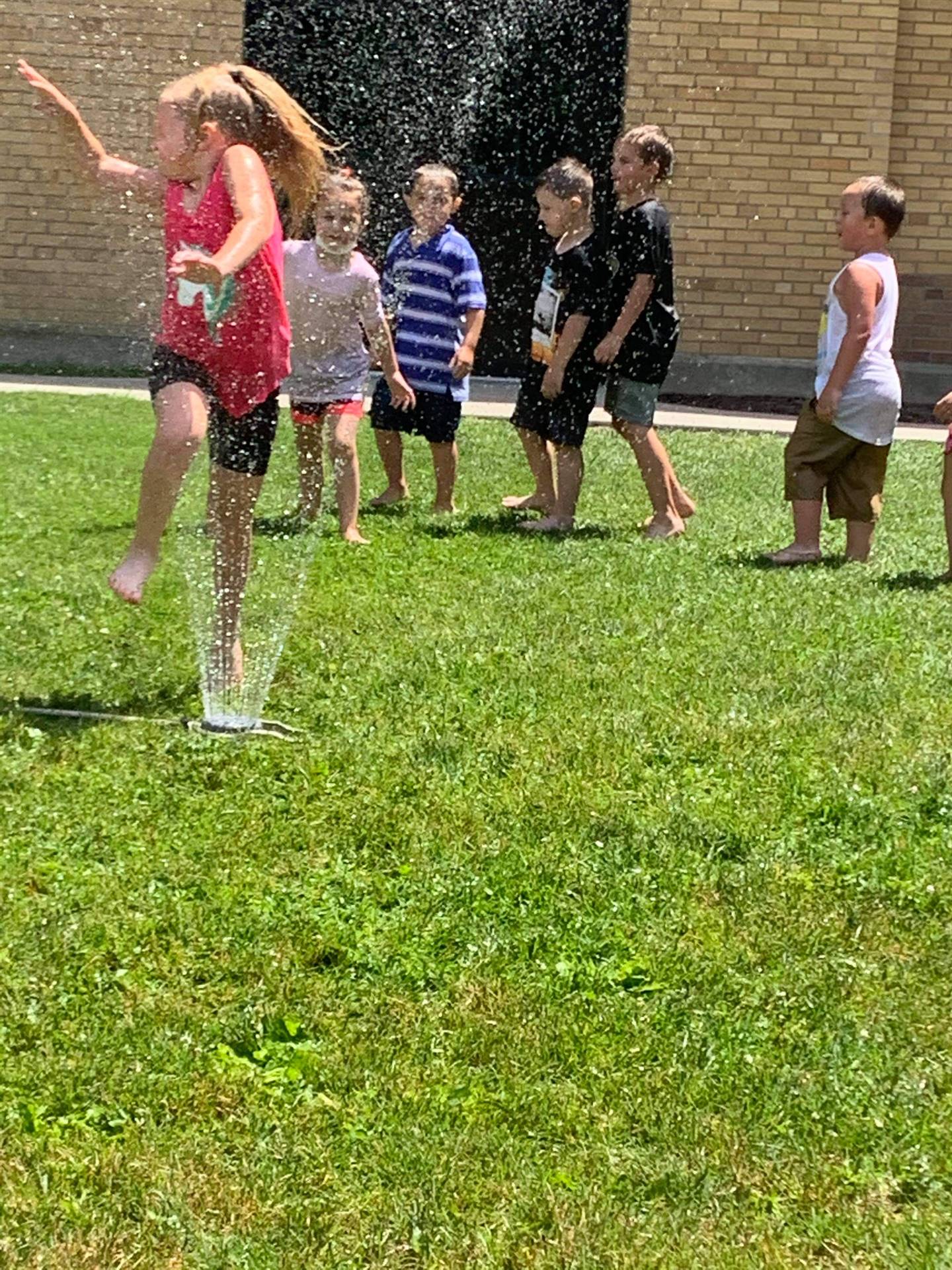 students running under sprinkler