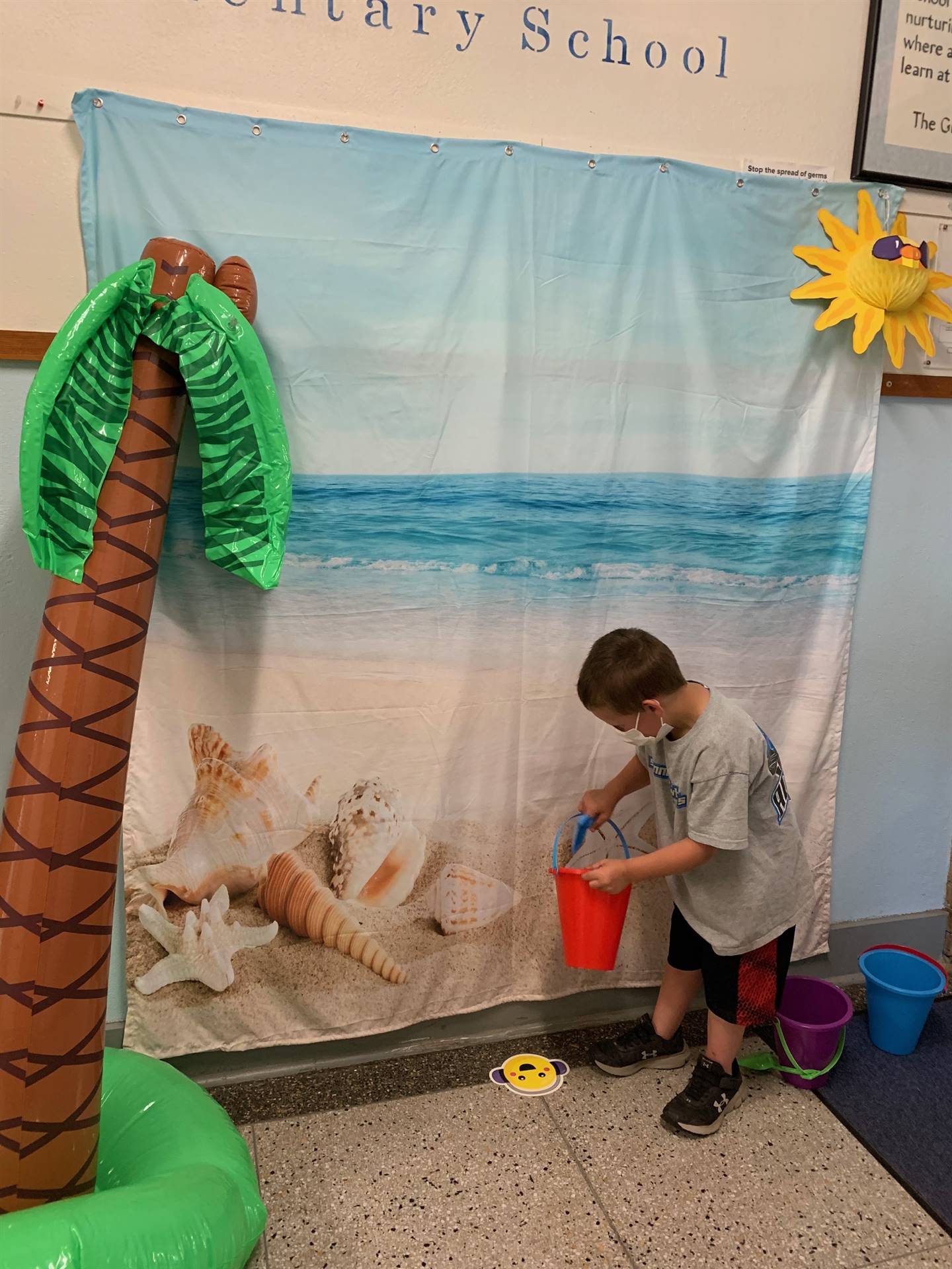 a student with a pail against a beach back drop