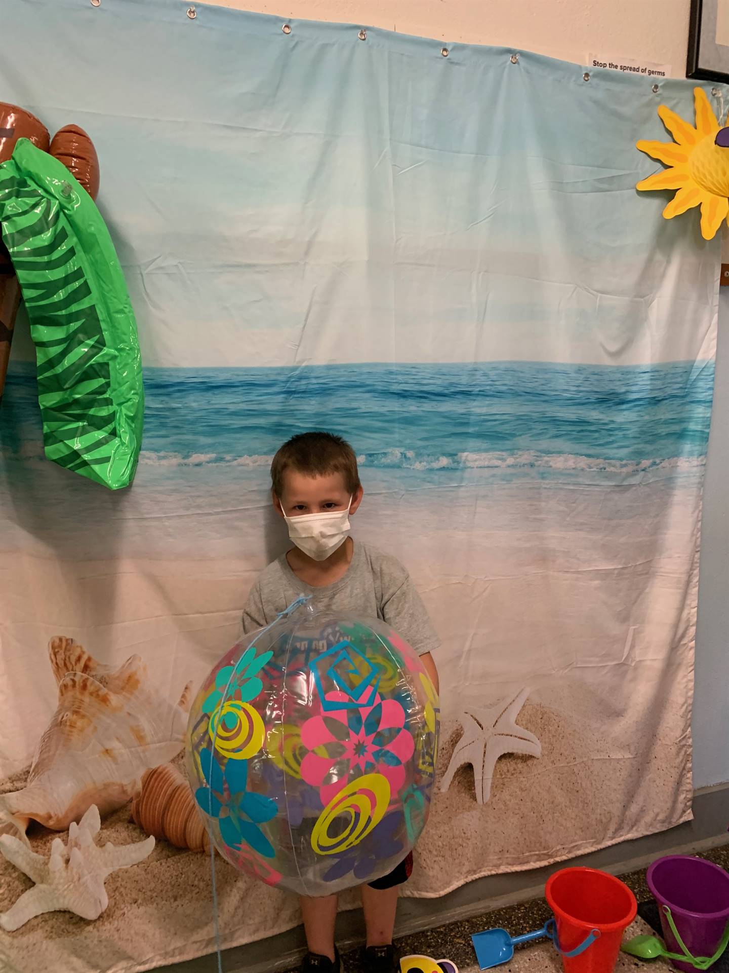 a student with a beach ball against a beach back drop