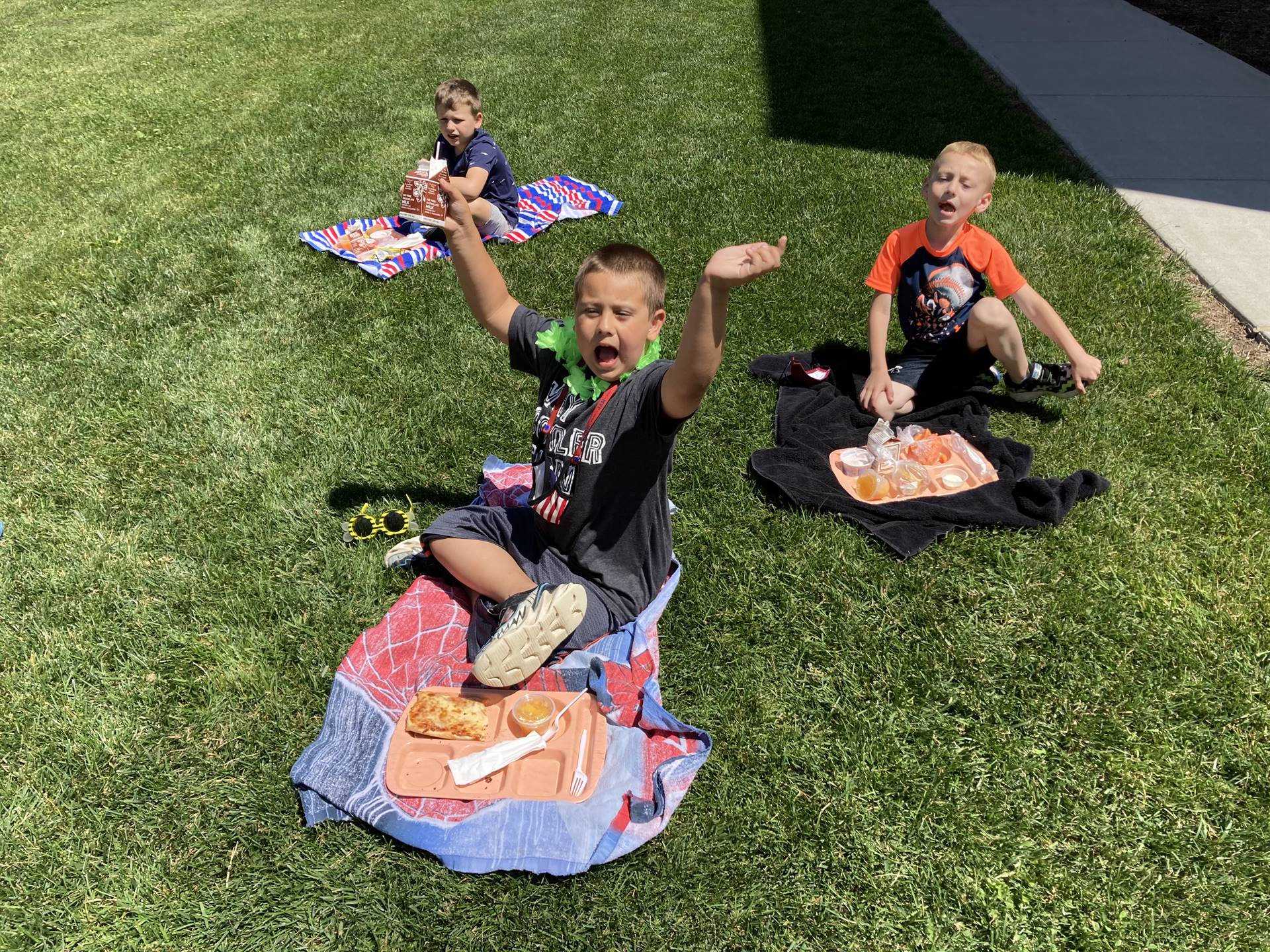 3 students on  beach towel soutside eating.