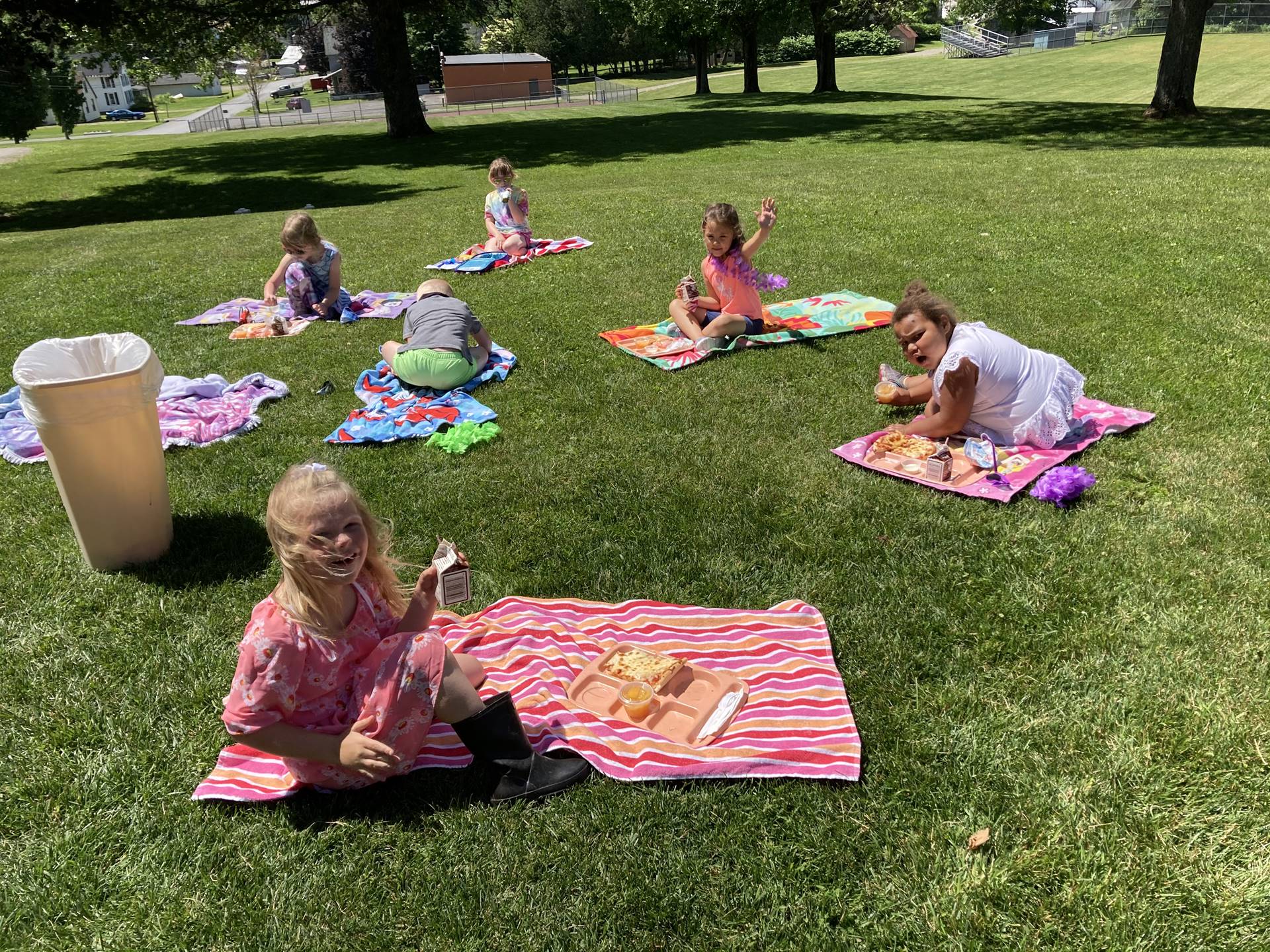  students on a beach towels outside eating.