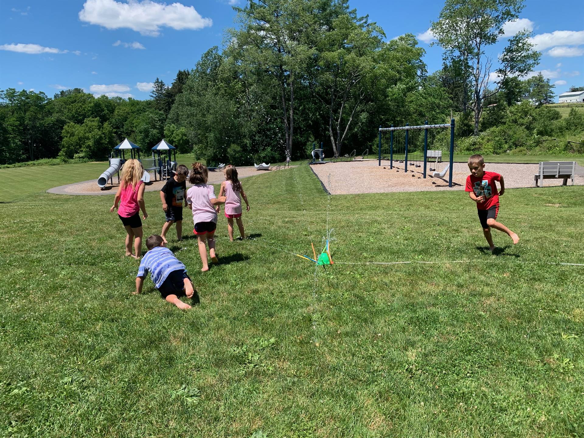 students run under sprinkler