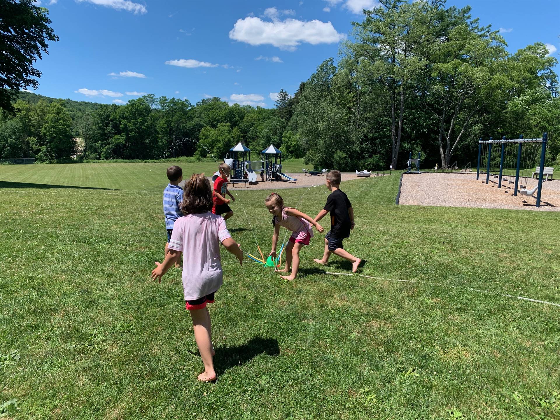 students run under sprinkler