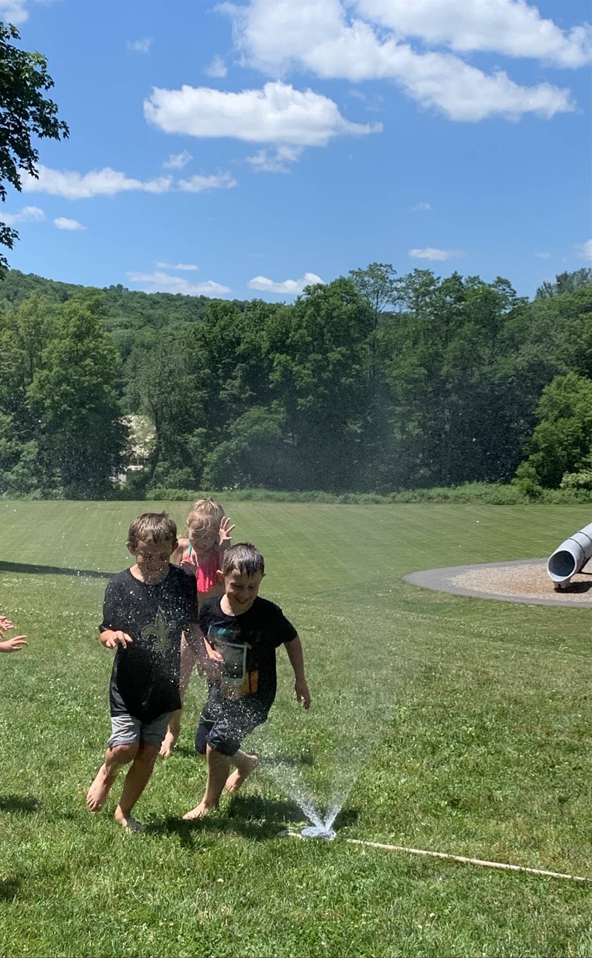 students run under sprinkler