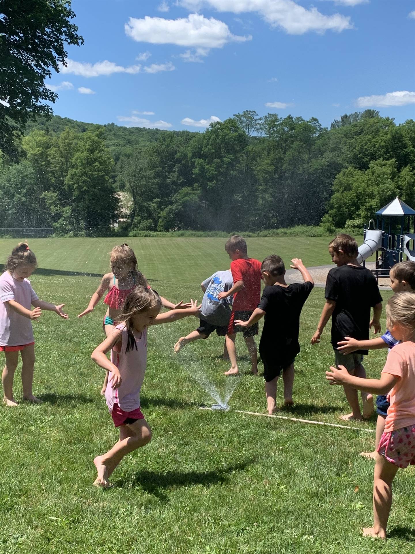 students run under sprinkler