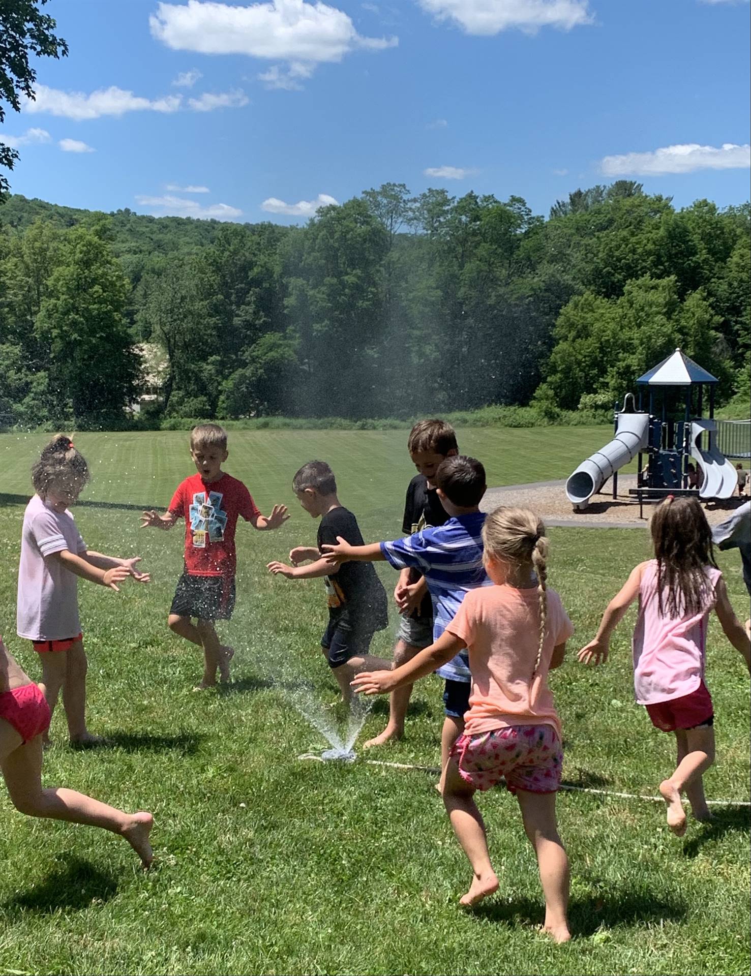 students run under sprinkler