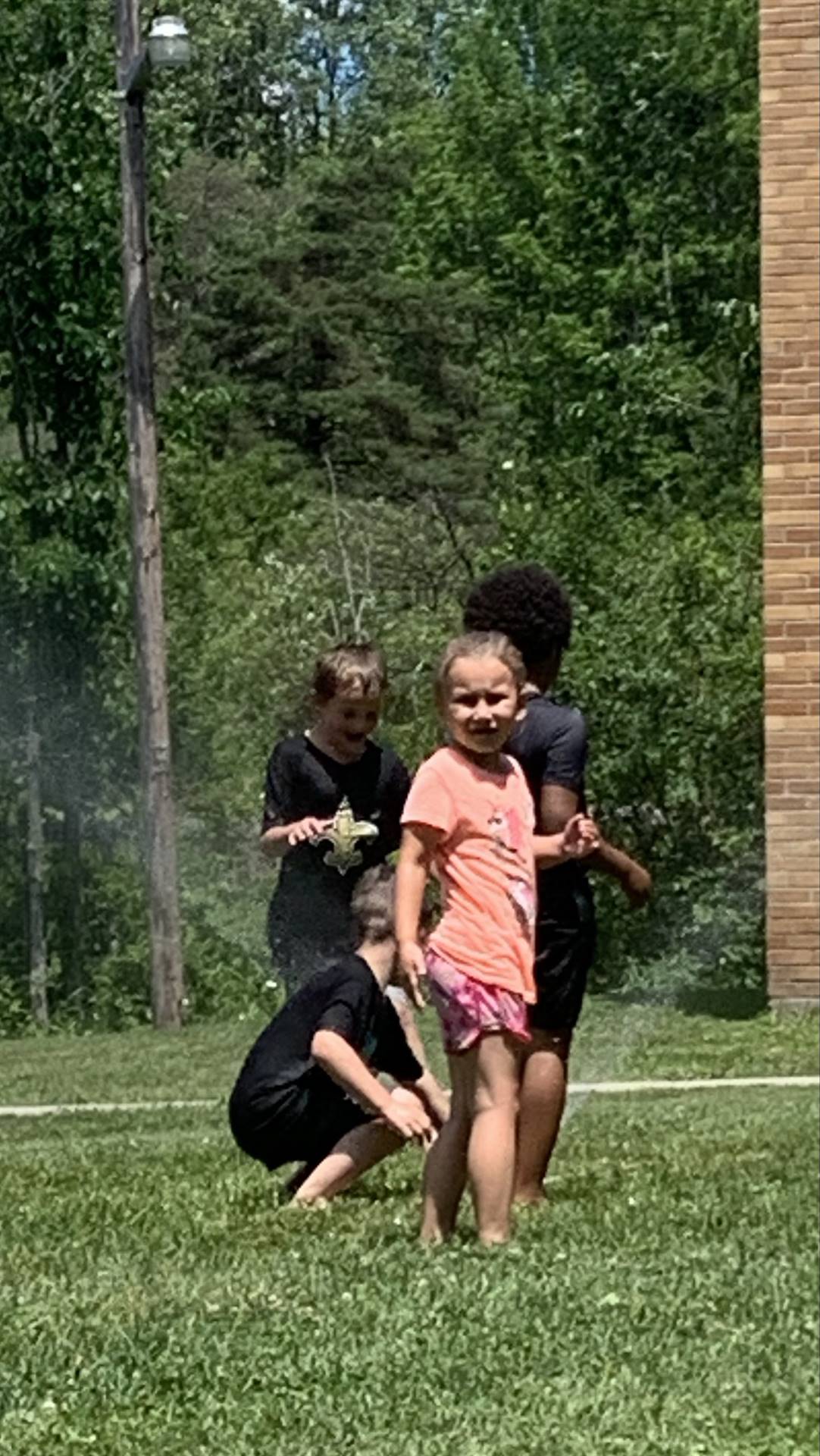 students run under sprinkler