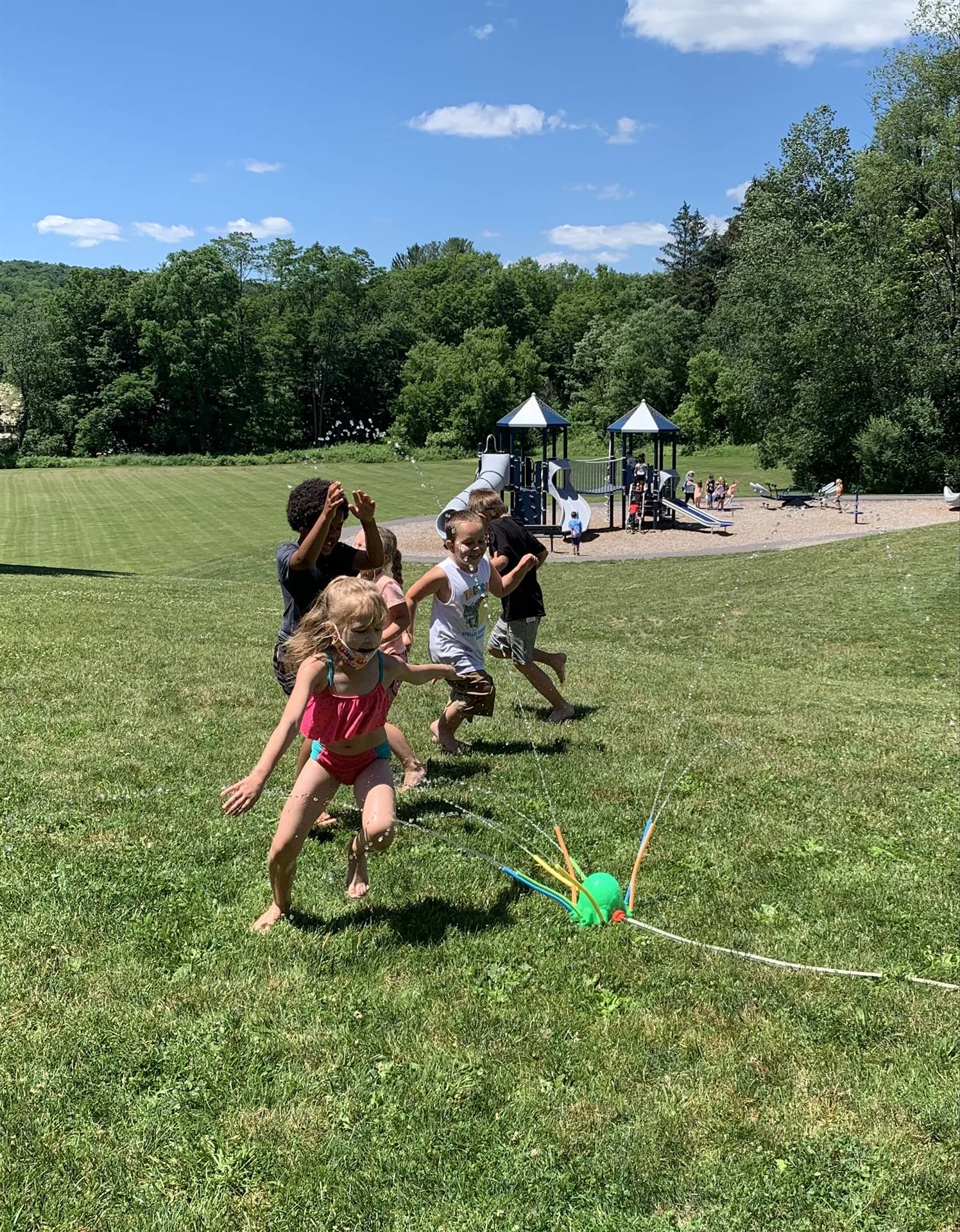 students run under sprinkler