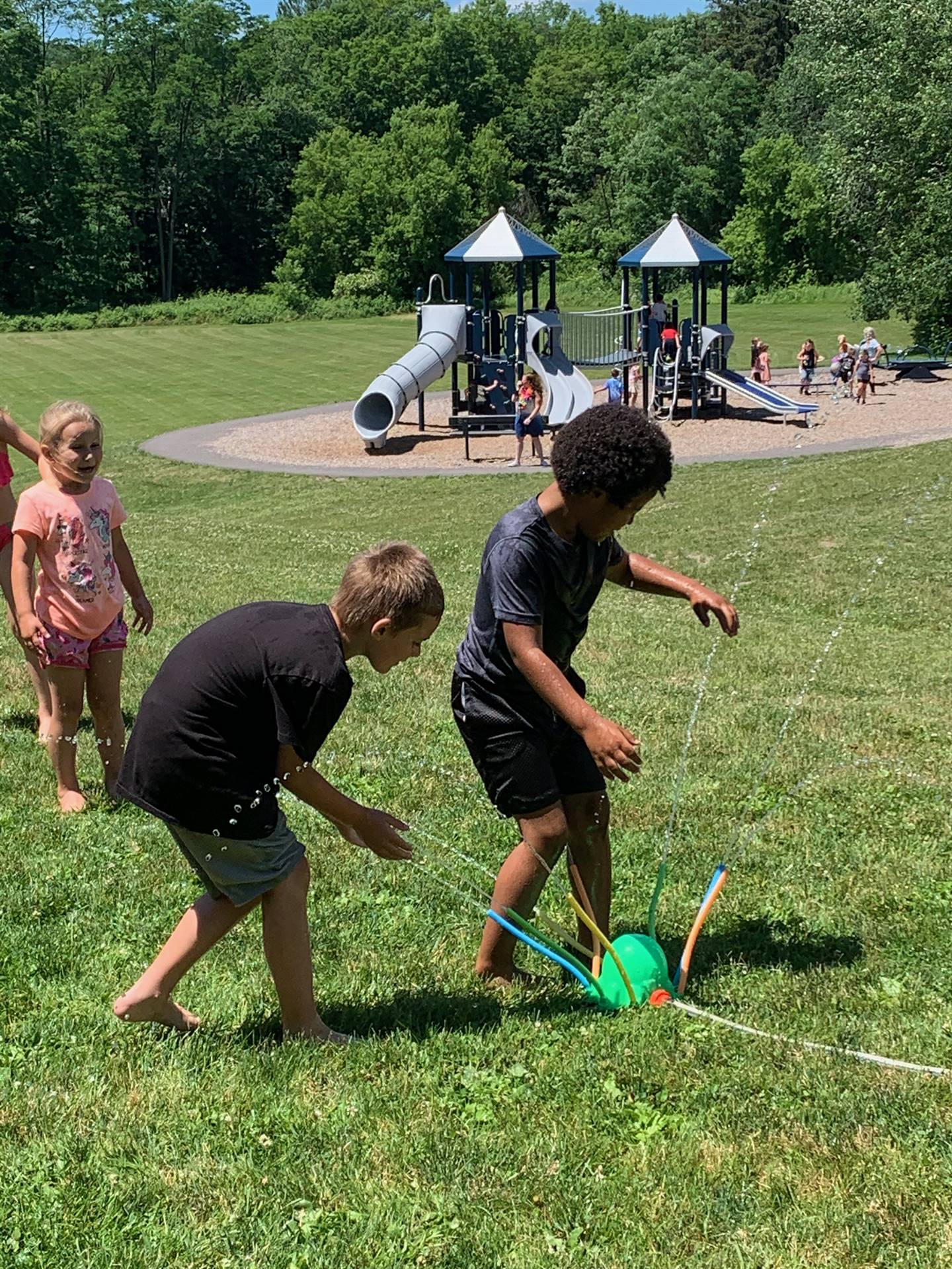 students run under sprinkler