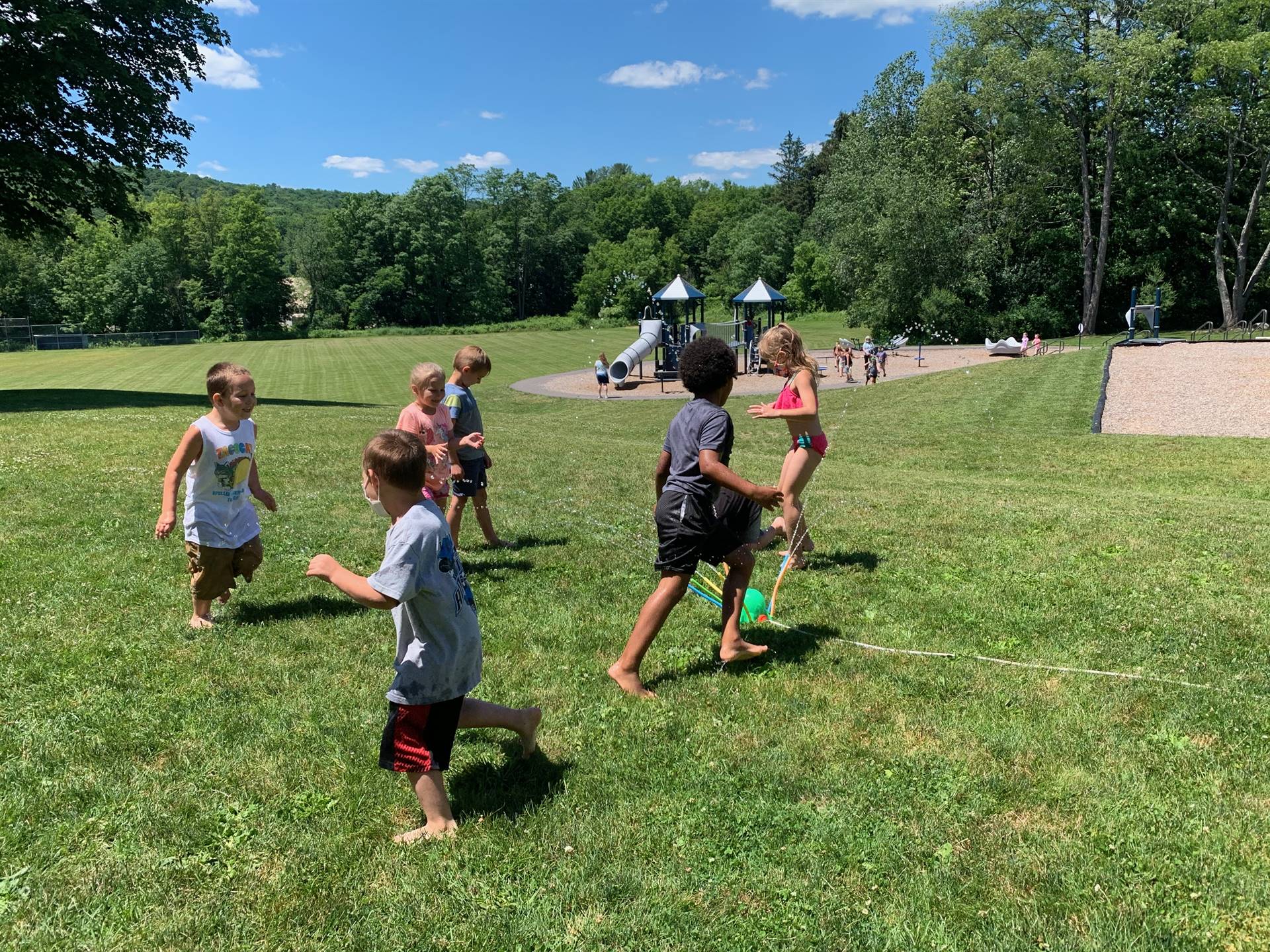 students run under sprinkler