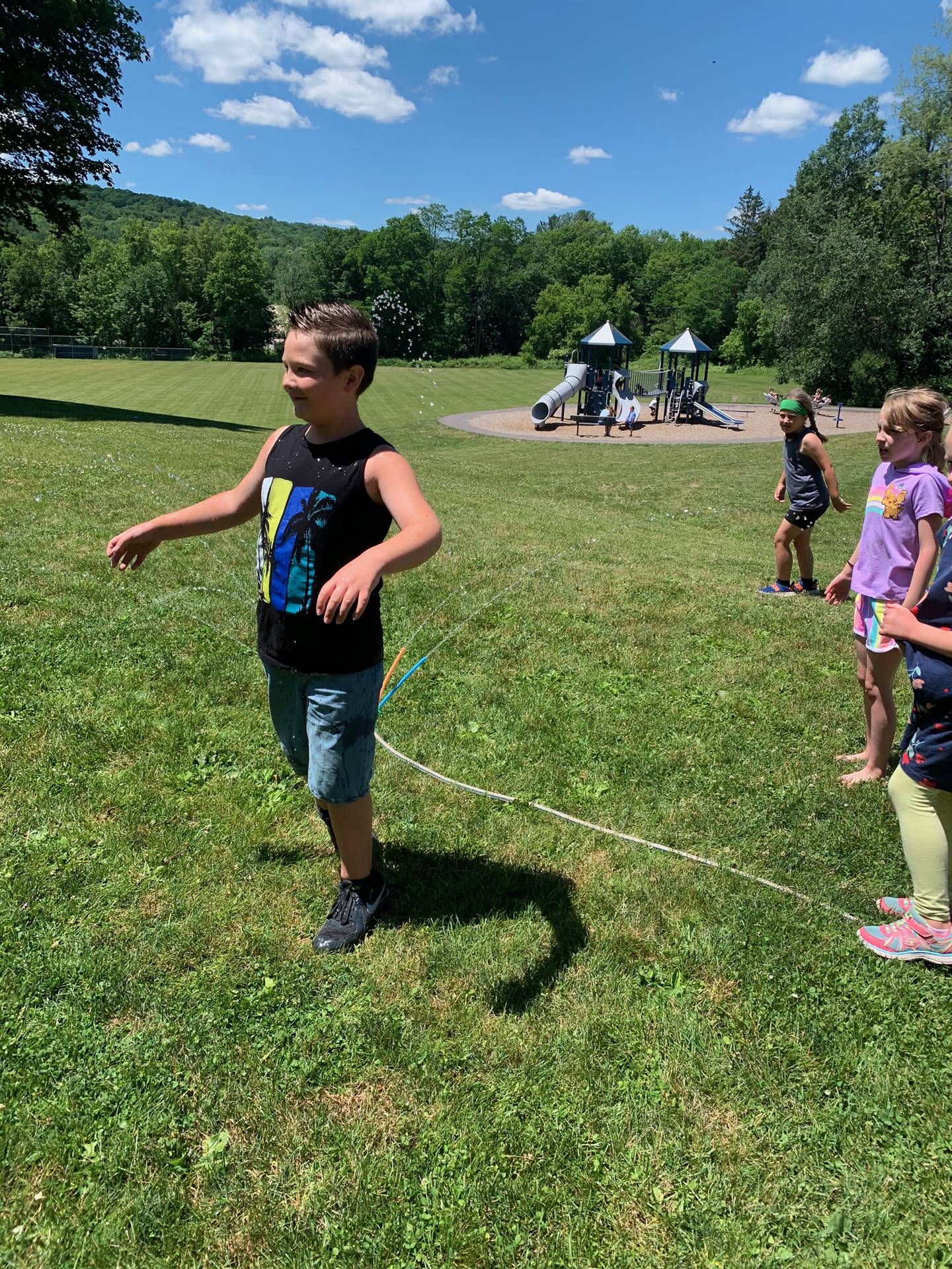 students run under sprinkler