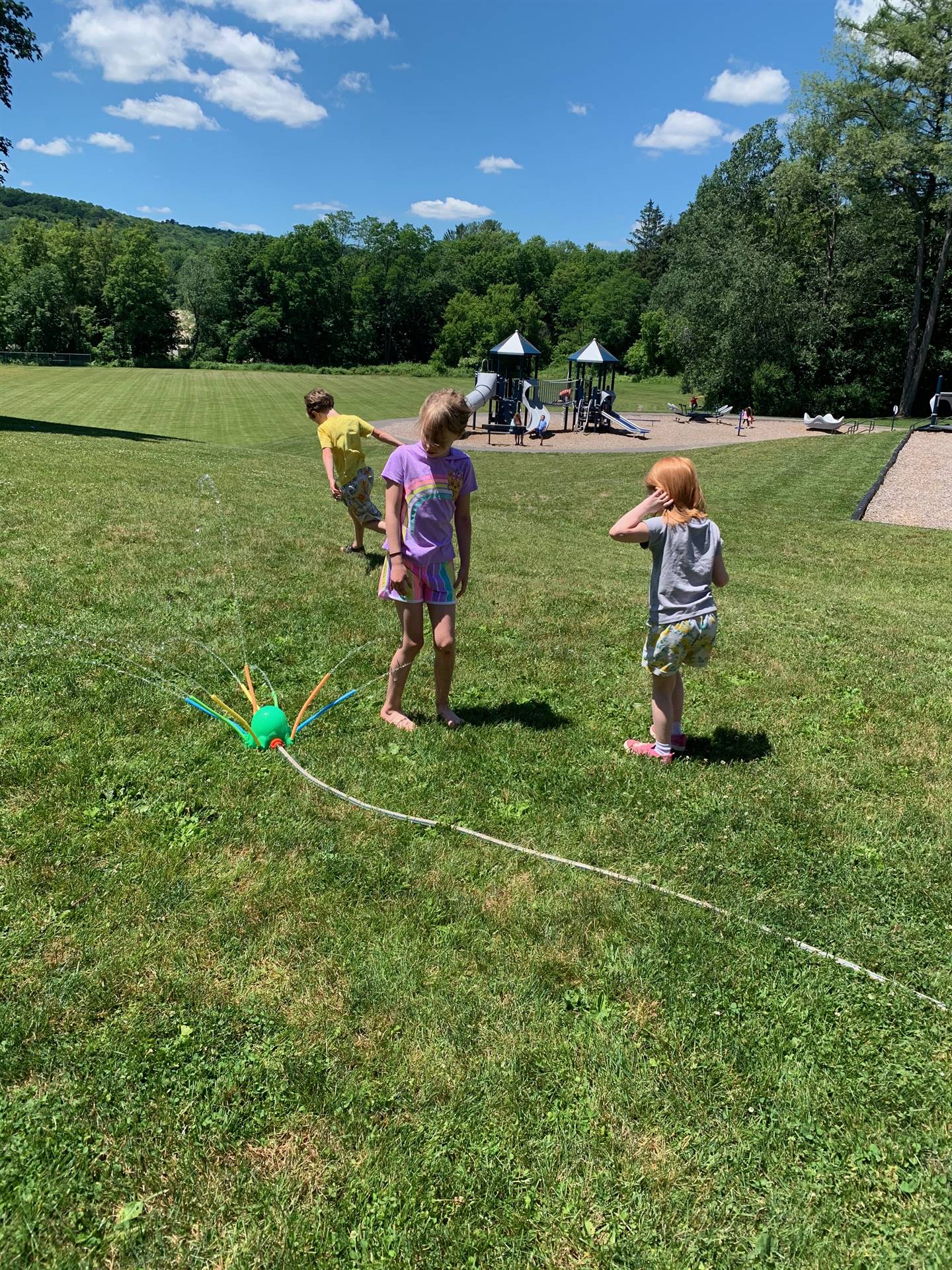 students run under sprinkler