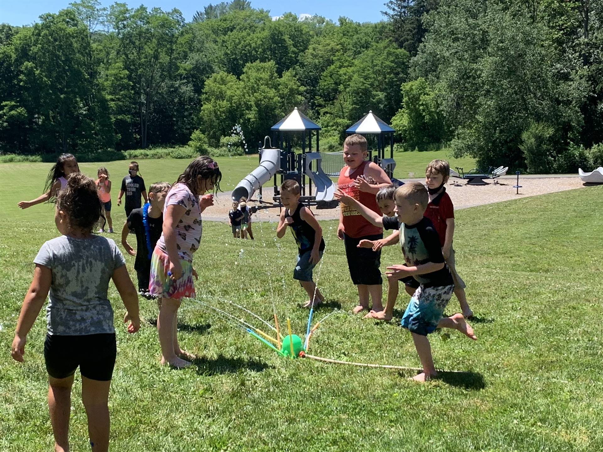 students running under sprinkler