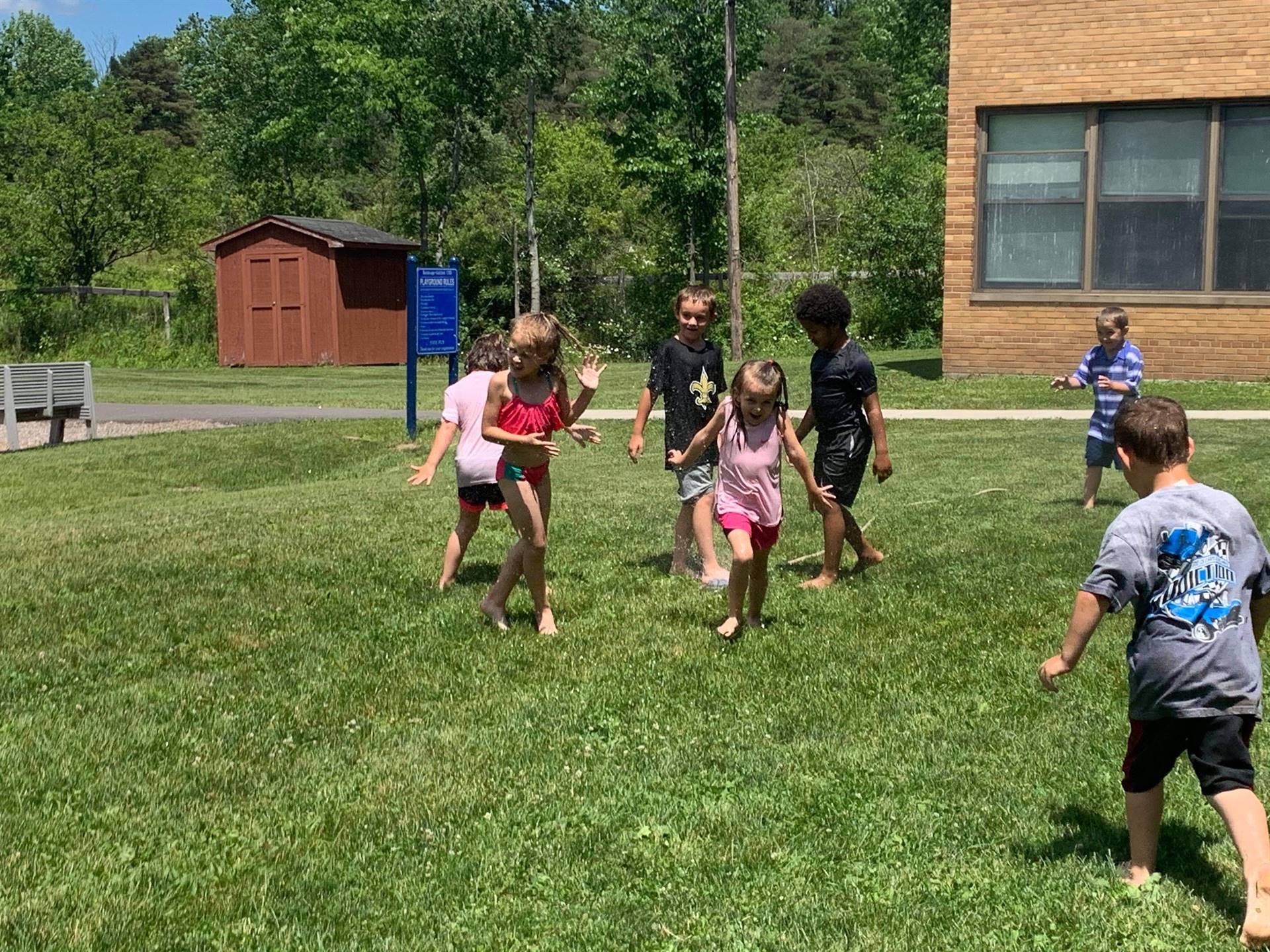 students running under sprinkler