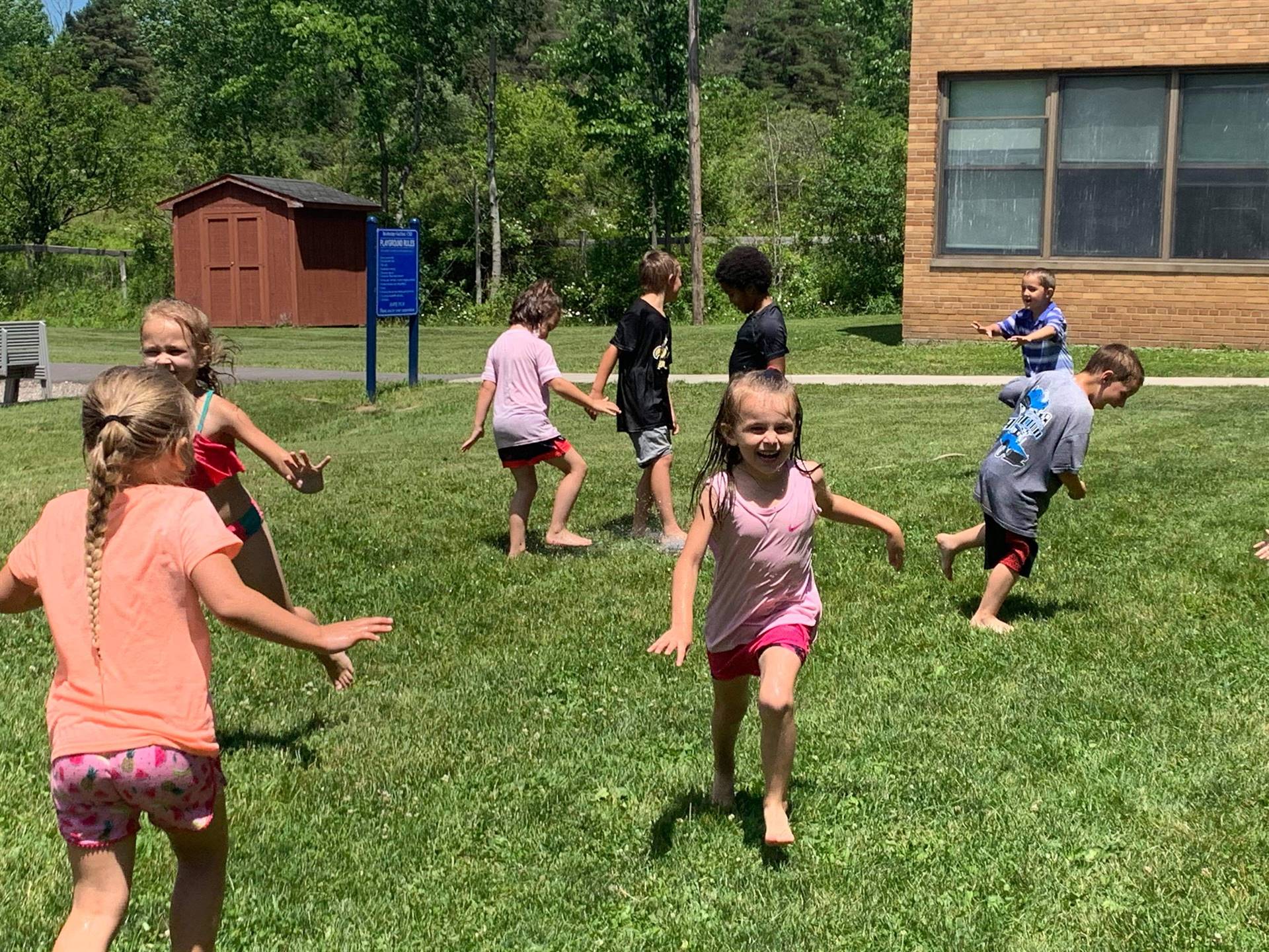 students running under sprinkler