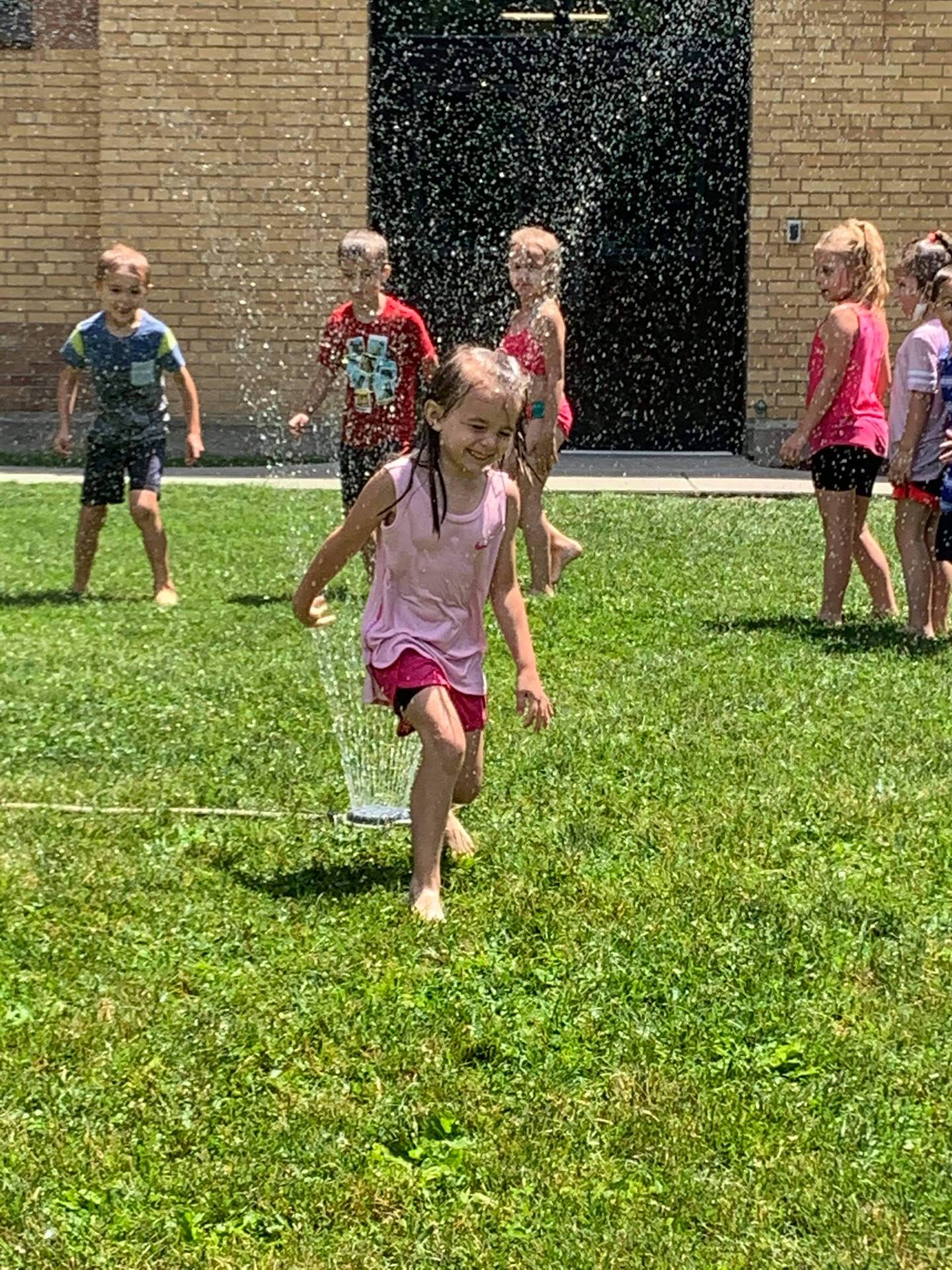 students running under sprinkler