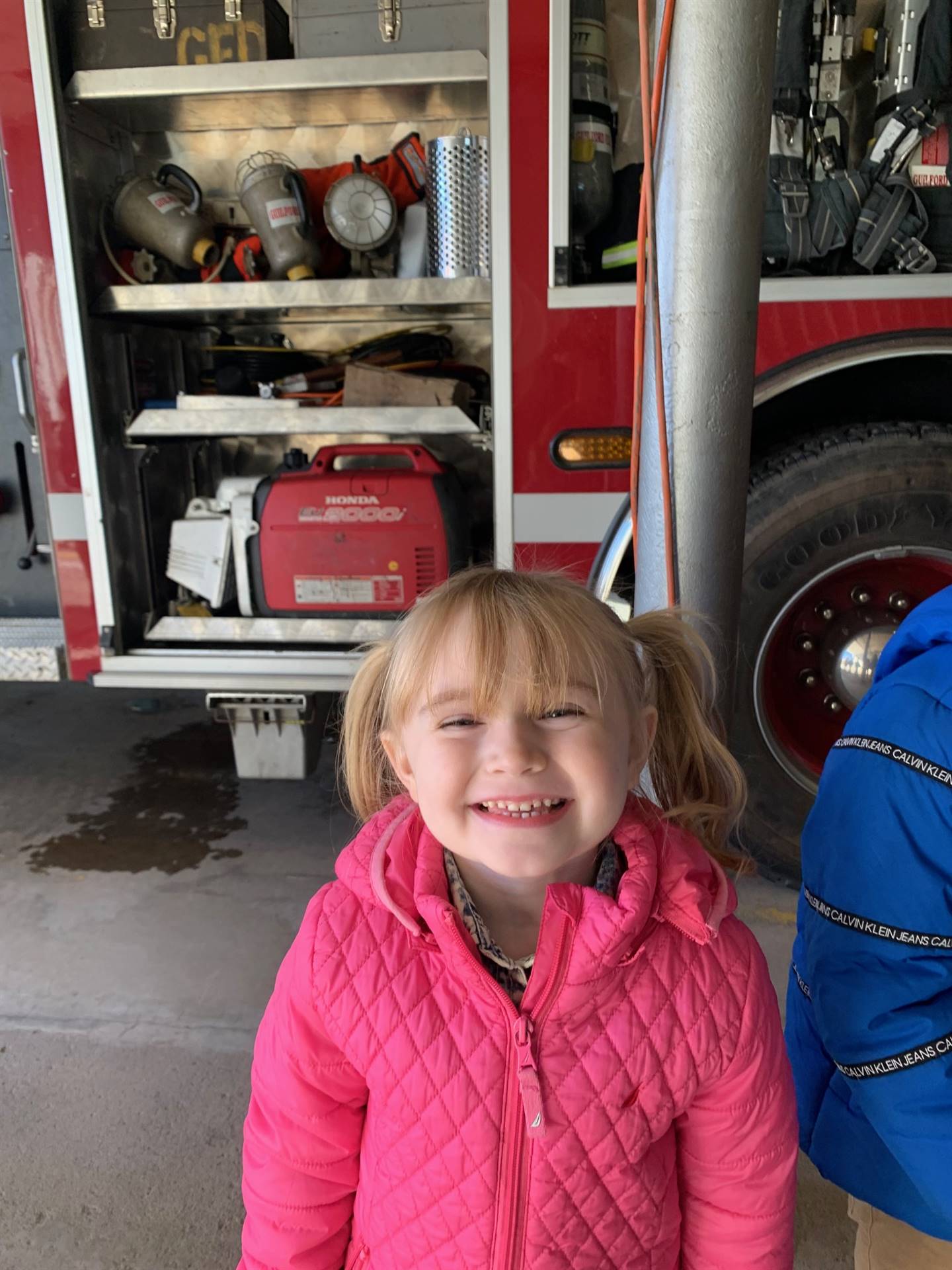 a girl with a big smile next to fire engine.