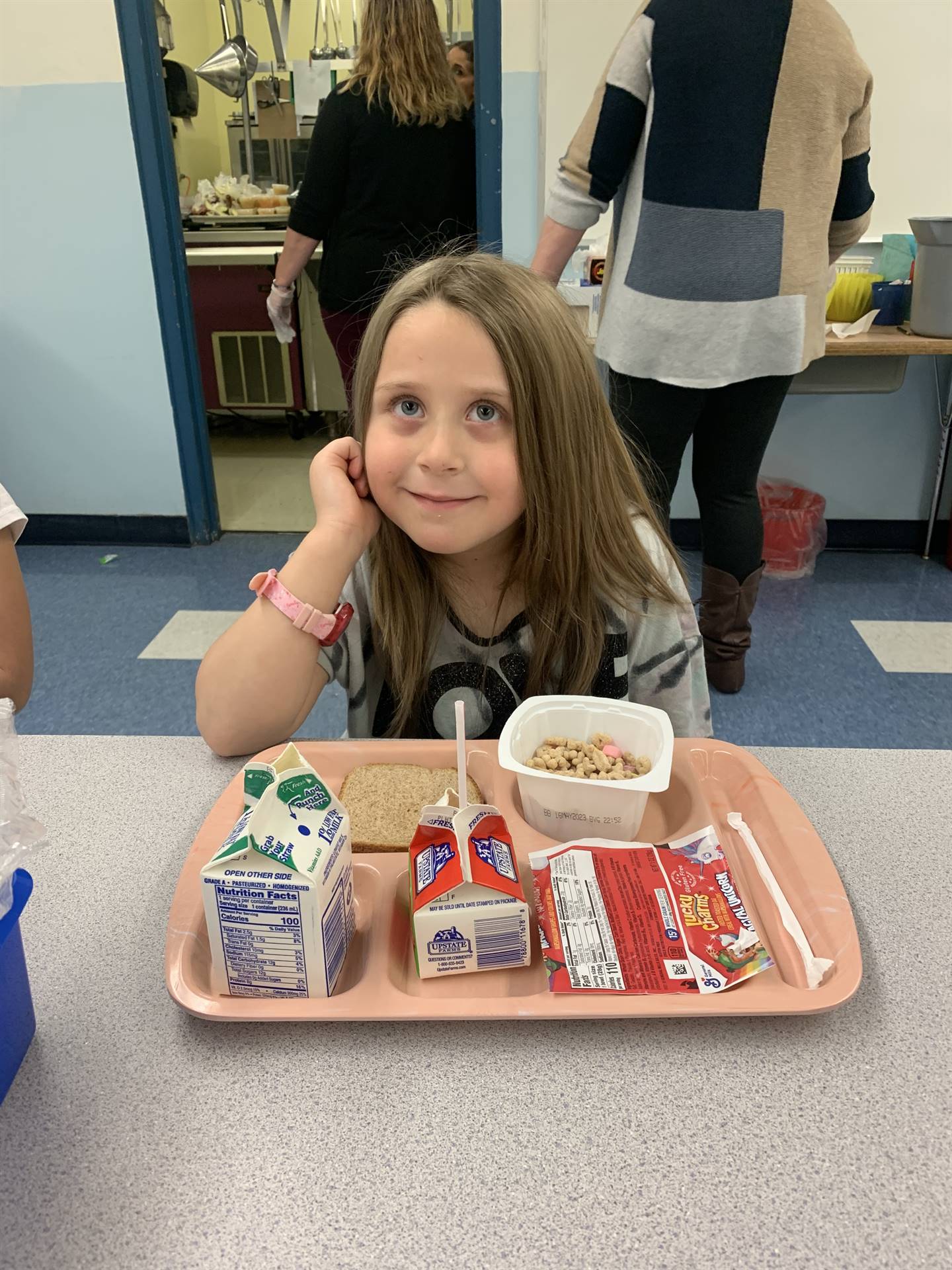 child with tray of food on table smiling