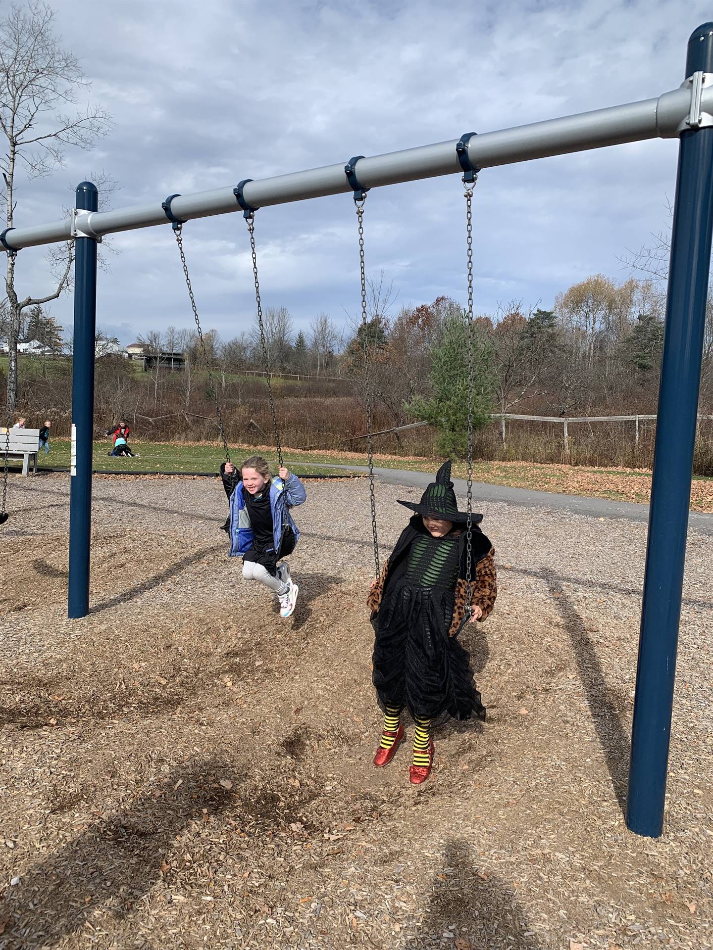 2 witches on playground swinging. 
