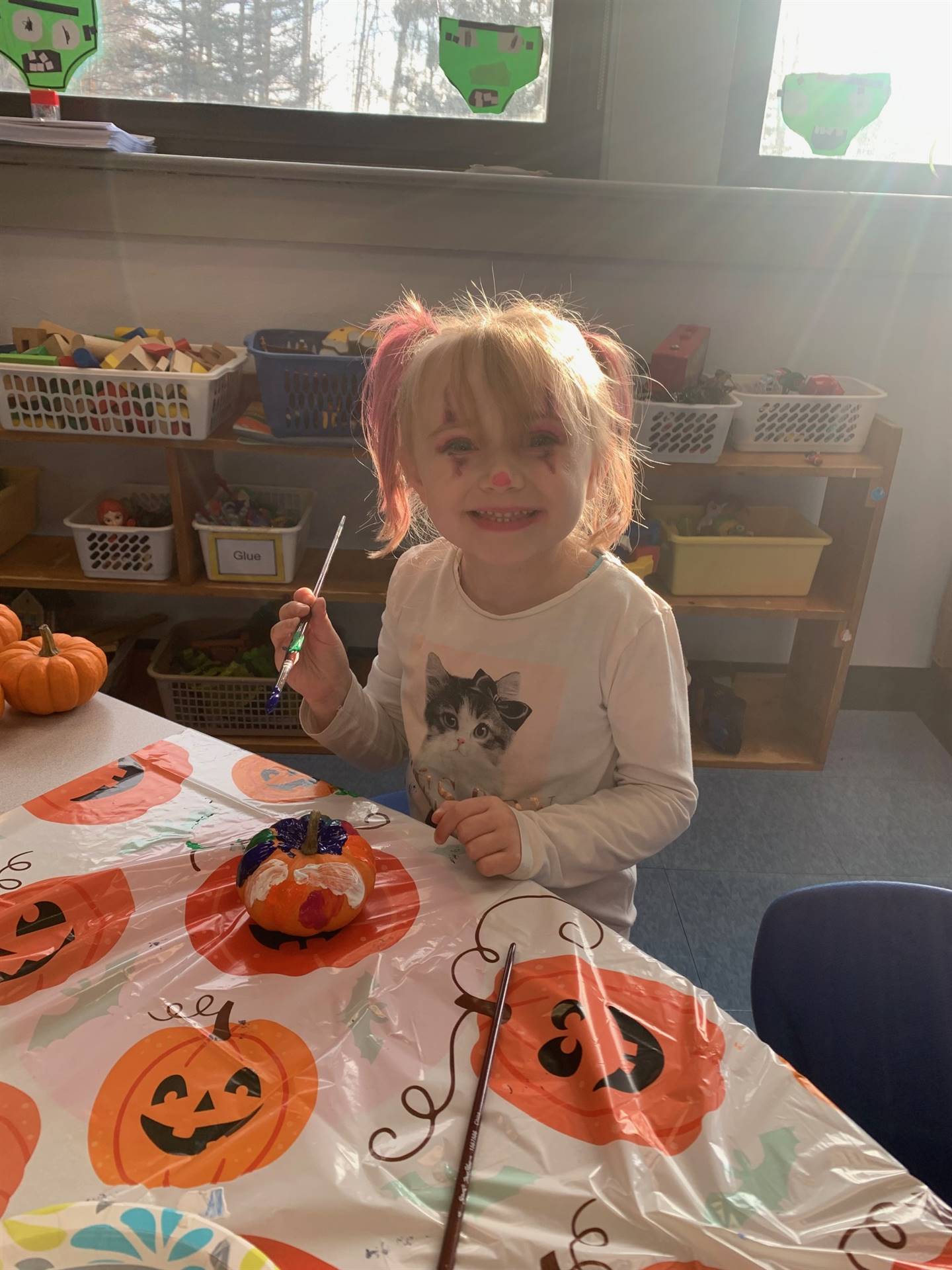 student painting a pumpkin on a pumpkin patterned tablecloth.