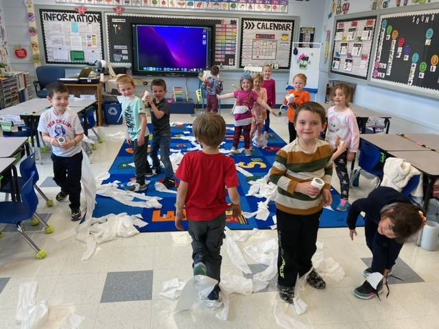 students playing a game with toilet paper in classroom.